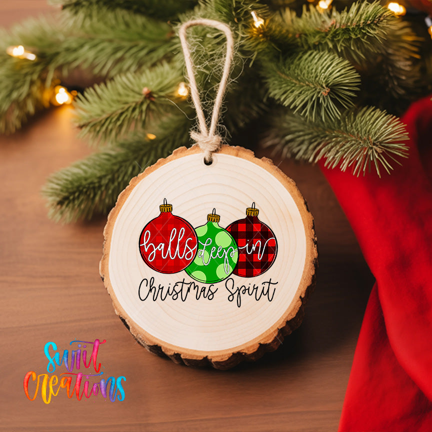A wooden ornament with the text "balls keep in christmas spirit" hanging on a Christmas tree, surrounded by pine branches and twinkling lights.