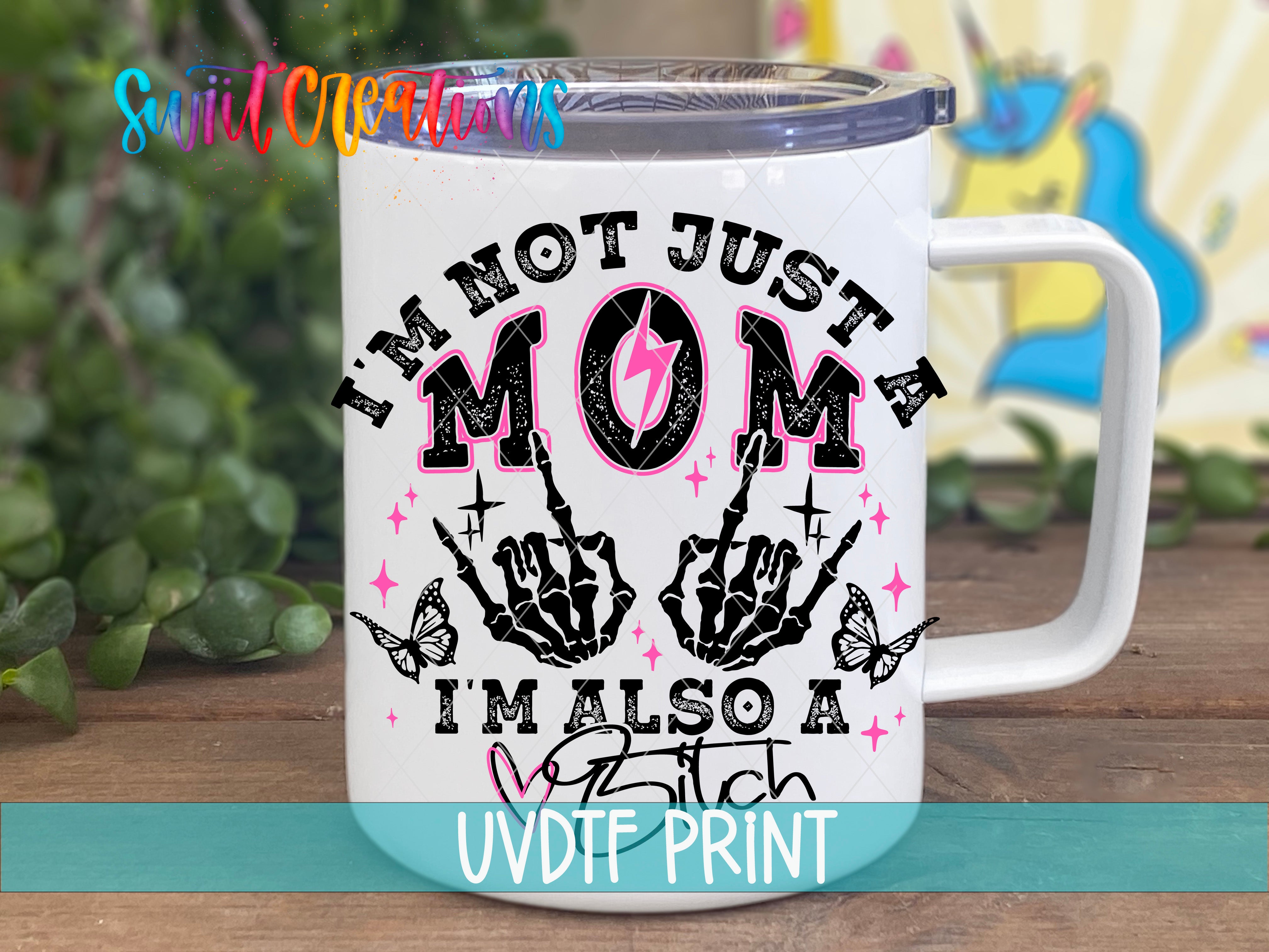 A white mug with a graphic design featuring a skeleton hand and the text "I'm not just a mom, I'm also a bitch" printed on it.