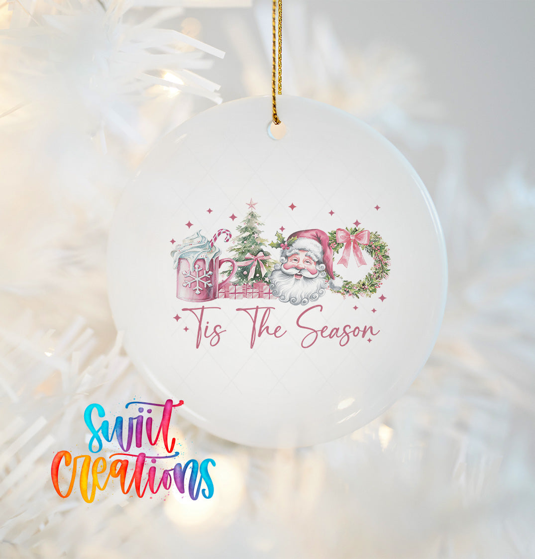 A white ceramic ornament with a Santa Claus design and the text "Tis the Season" hanging on a string.