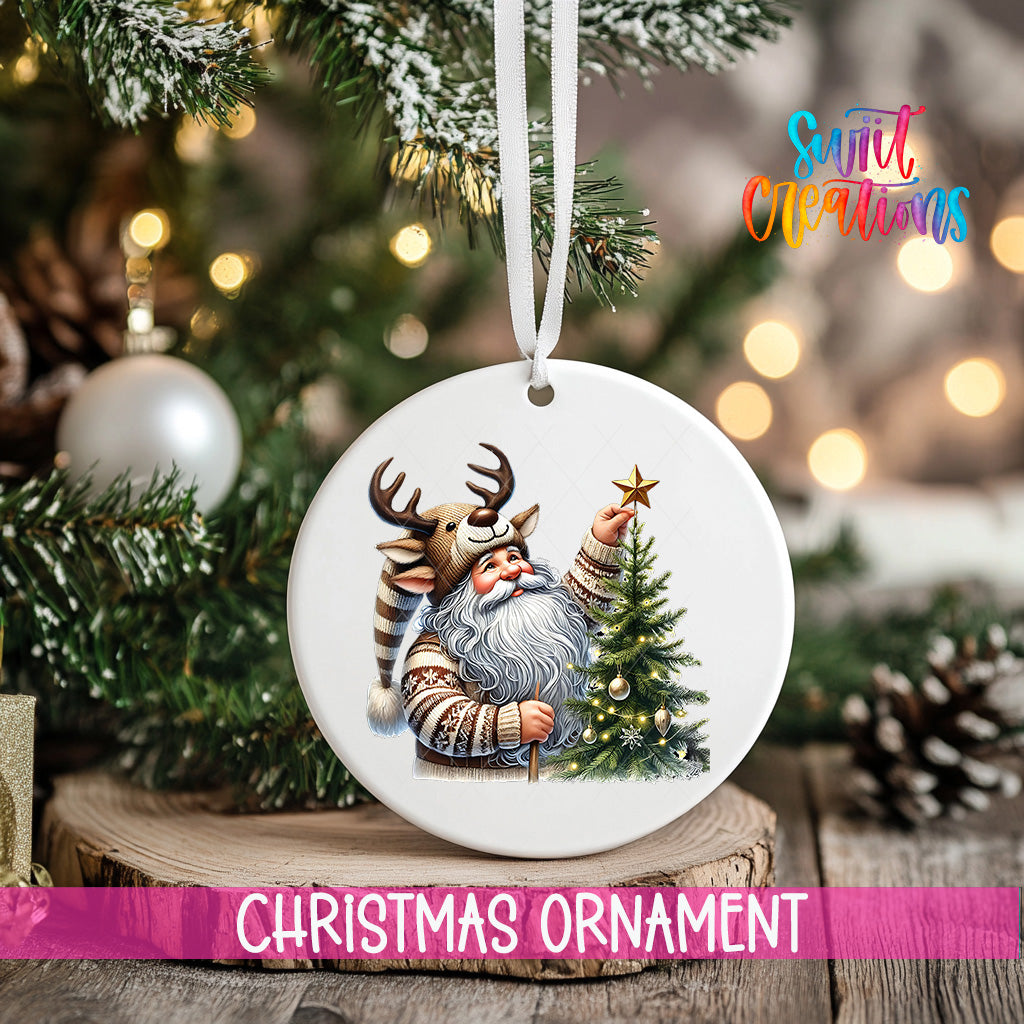 A white Christmas ornament featuring a Santa Claus figure holding a star, surrounded by a decorated Christmas tree and pine cones.