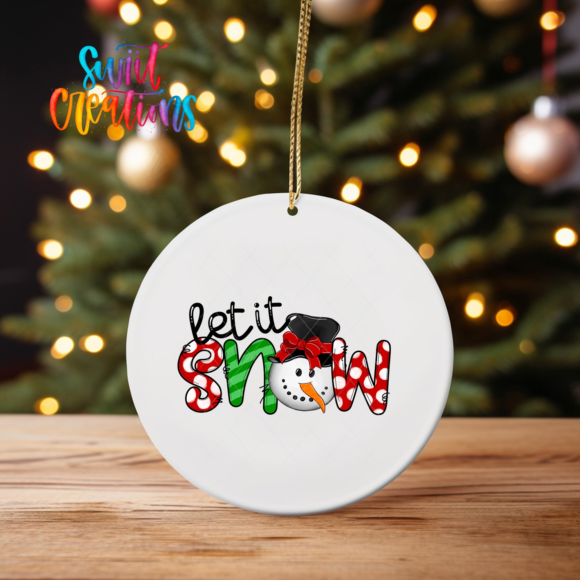 A white ceramic ornament with the text "let it snow" and a snowman graphic, hanging on a string.