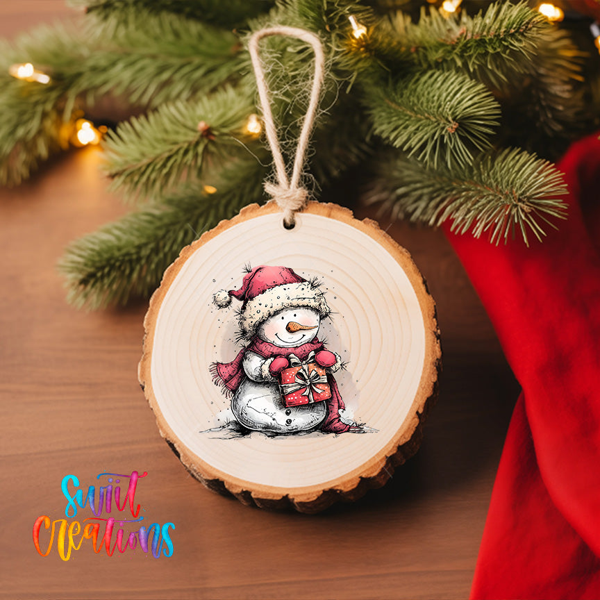 A wooden ornament featuring a snowman is hanging on a Christmas tree, with a red cloth visible in the background.
