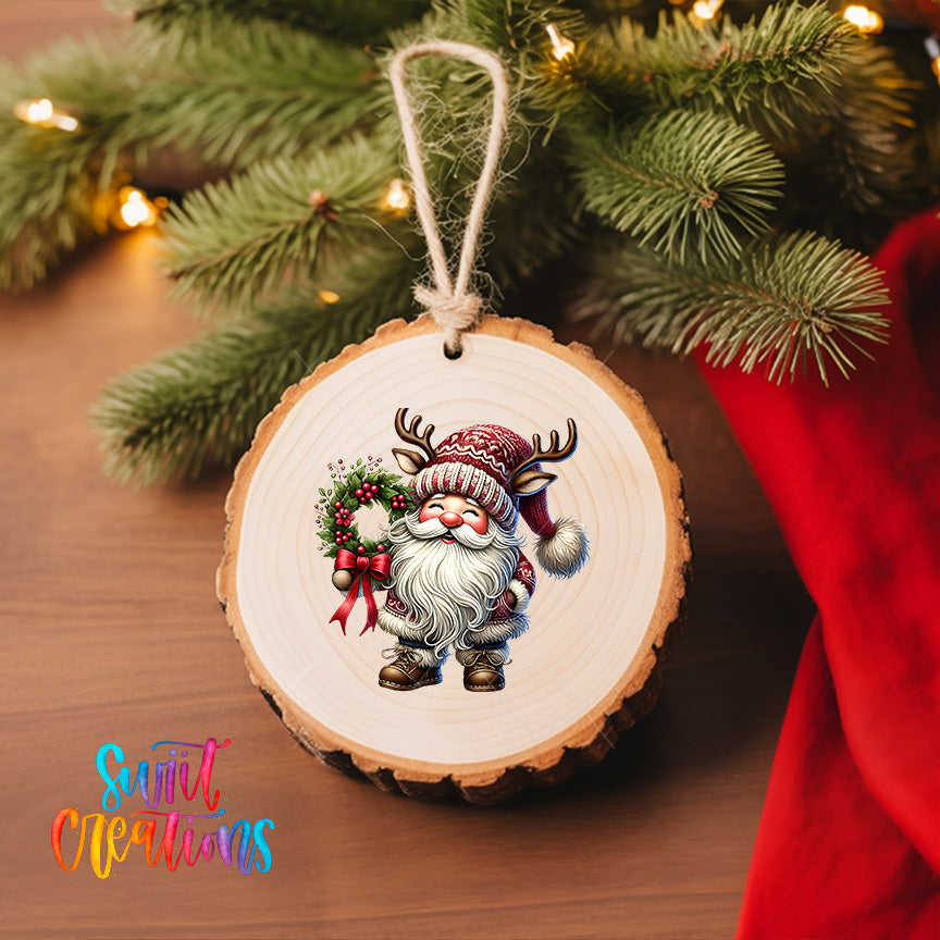 A wooden ornament featuring a smiling gnome holding a wreath and wearing a Santa hat, hanging on a Christmas tree.