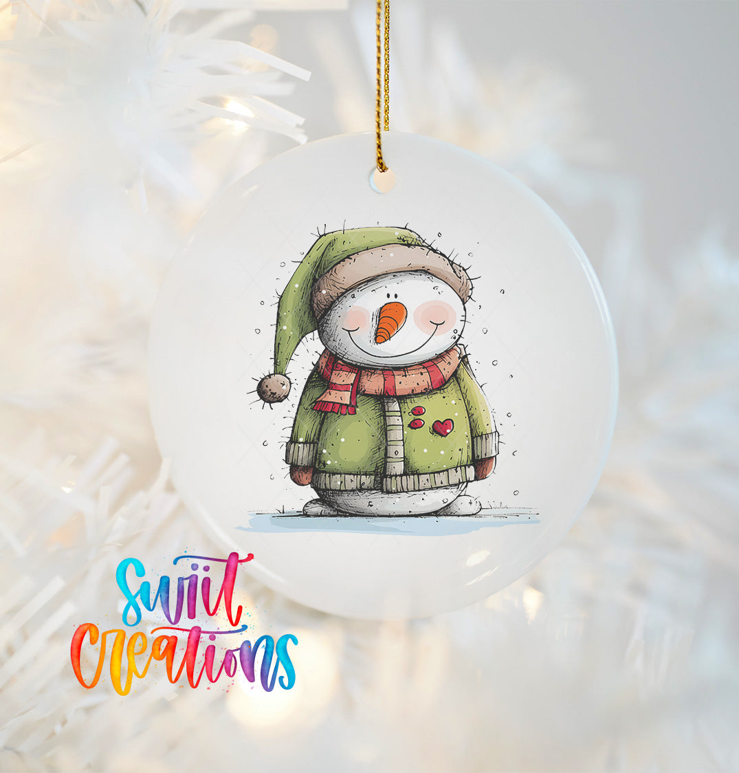 A white ornament featuring a snowman with a green hat and scarf, along with a red heart on its chest, is hanging on a Christmas tree.
