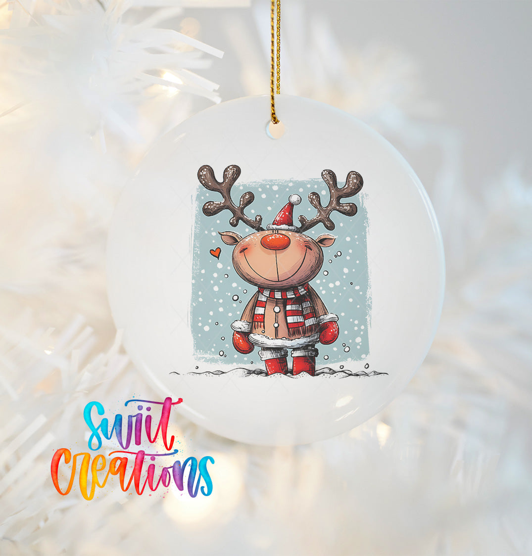 A white ornament featuring a smiling reindeer wearing a red and white striped scarf and hat, with snow falling around it, hanging on a Christmas tree.