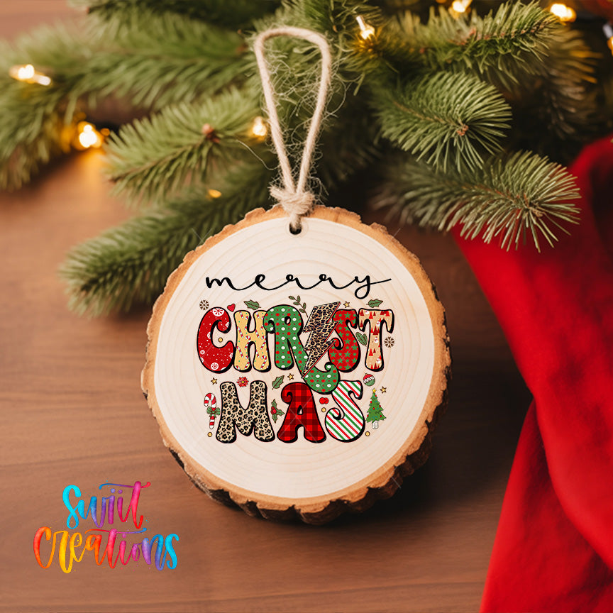 A wooden ornament with the text "Merry Christmas" is hanging on a Christmas tree, surrounded by pine branches and twinkling lights.