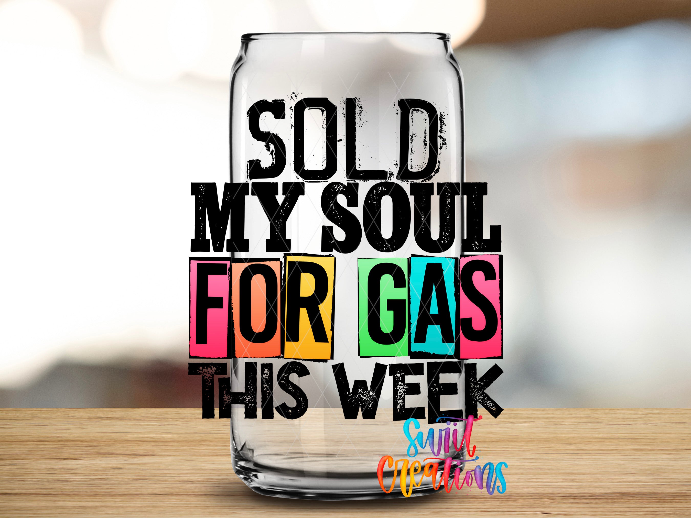 a clear glass can with text on it, placed on a wooden surface.