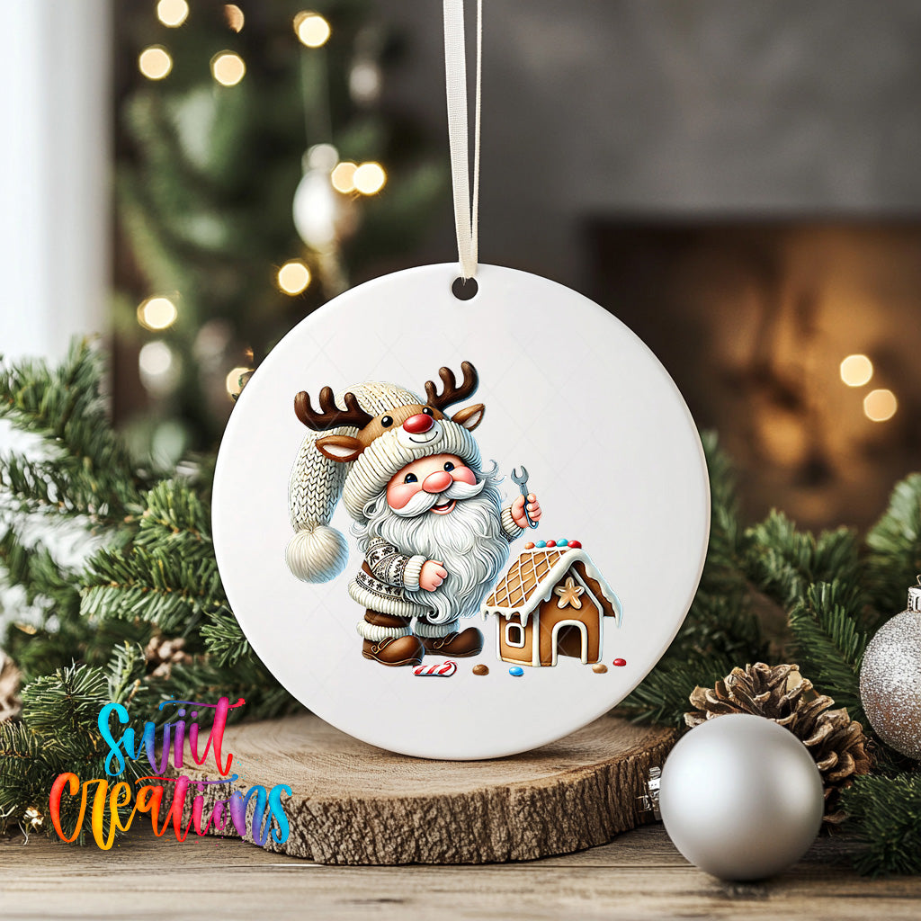 A white ceramic ornament featuring a Santa Claus figure with antlers and a gingerbread house, surrounded by Christmas decorations such as pine branches and ornaments.