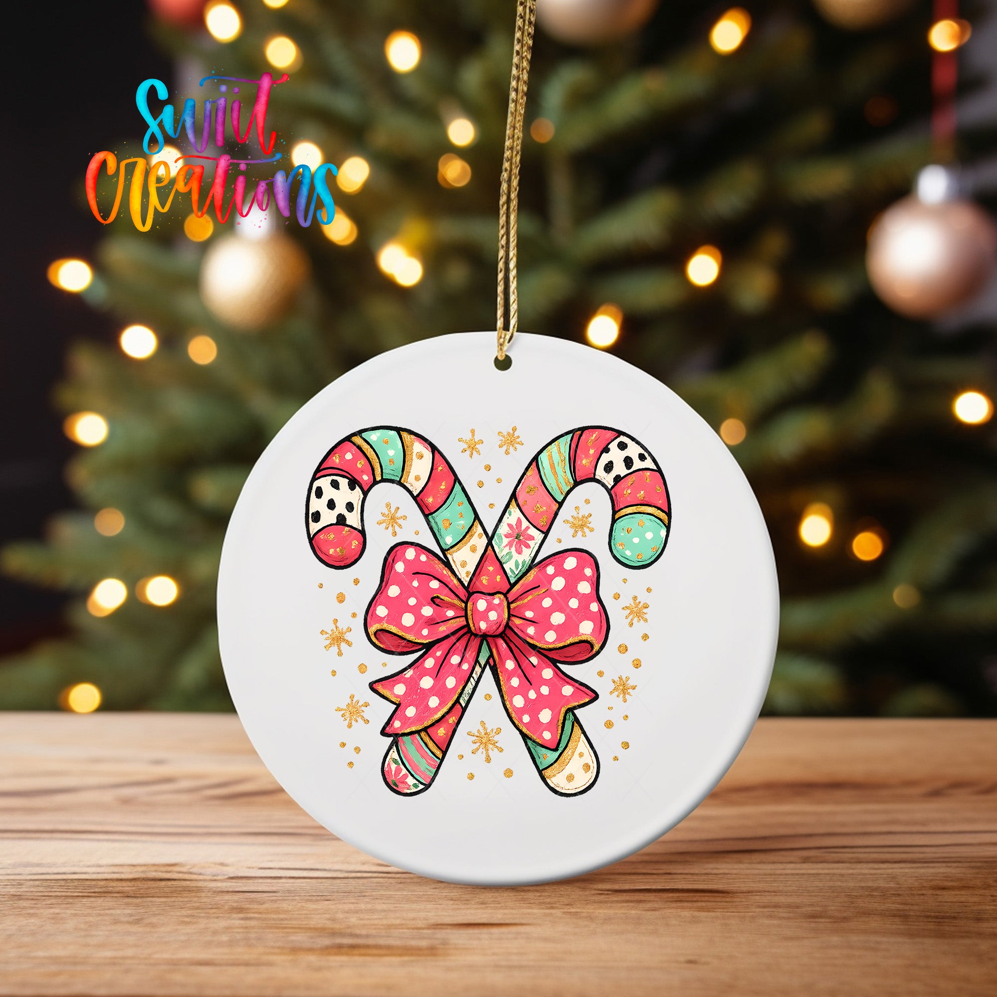 A white ornament with a colorful candy cane design and a pink bow is displayed on a wooden surface, with a blurred background of a Christmas tree and twinkling lights.