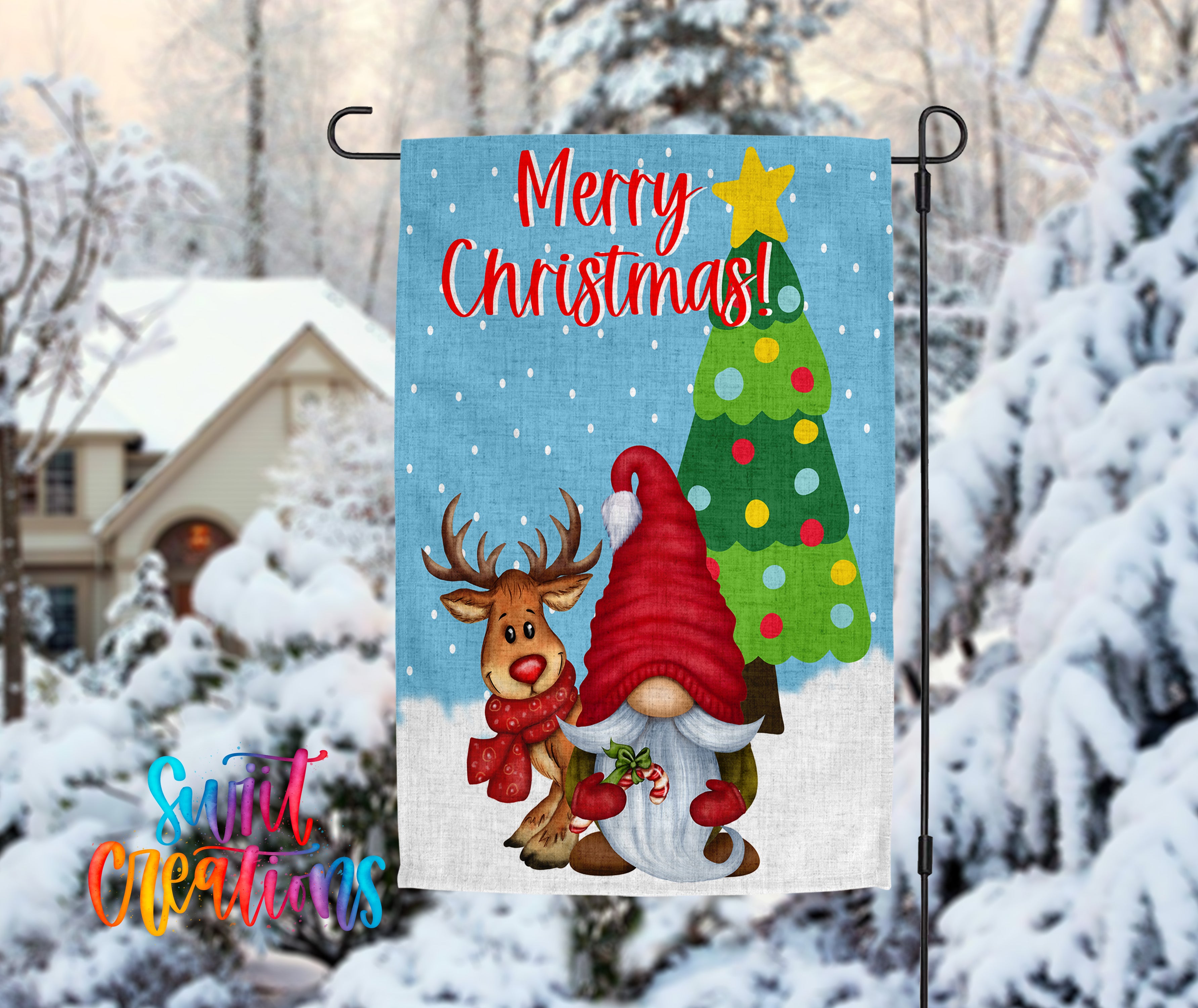 A festive Christmas-themed garden flag featuring a gnome and a reindeer, with a snow-covered house and trees in the background.