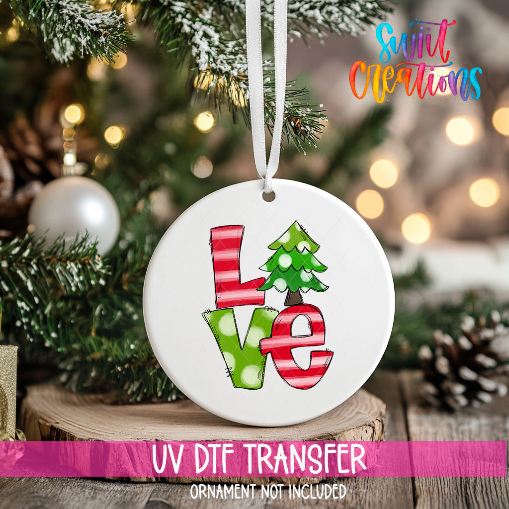 A white ceramic ornament with the word "LOVE" written on it, hanging on a Christmas tree.
