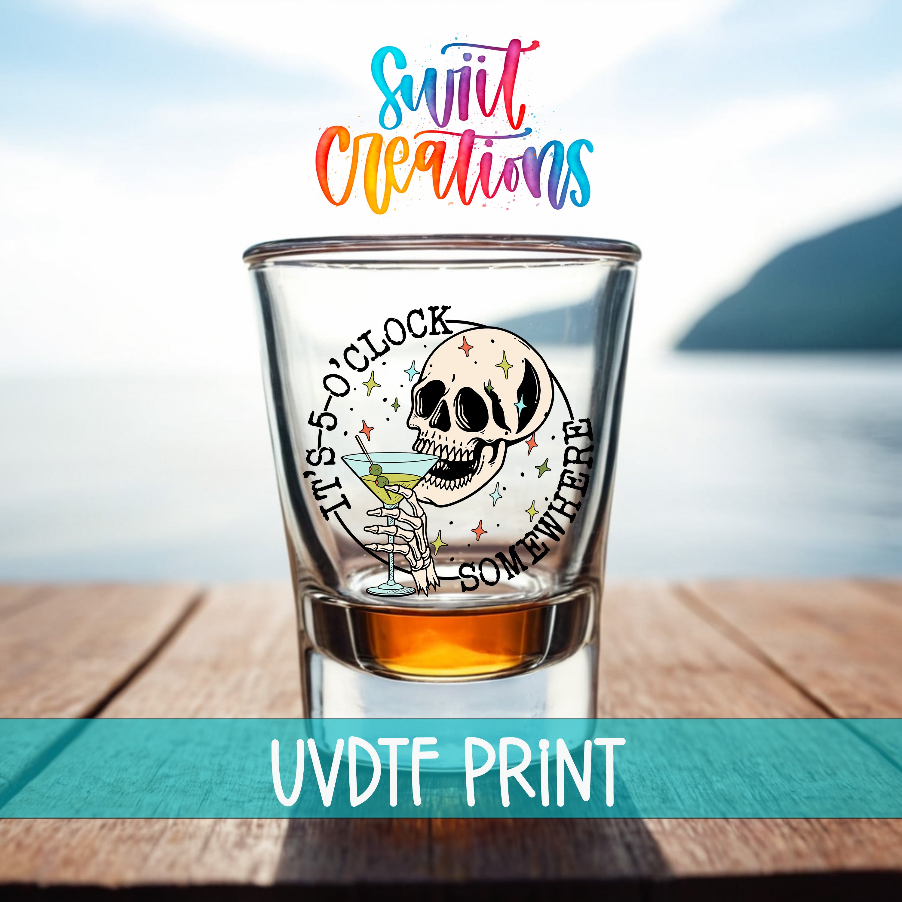 a shot glass with a skull and a cocktail glass, placed on a wooden surface with a body of water in the background.