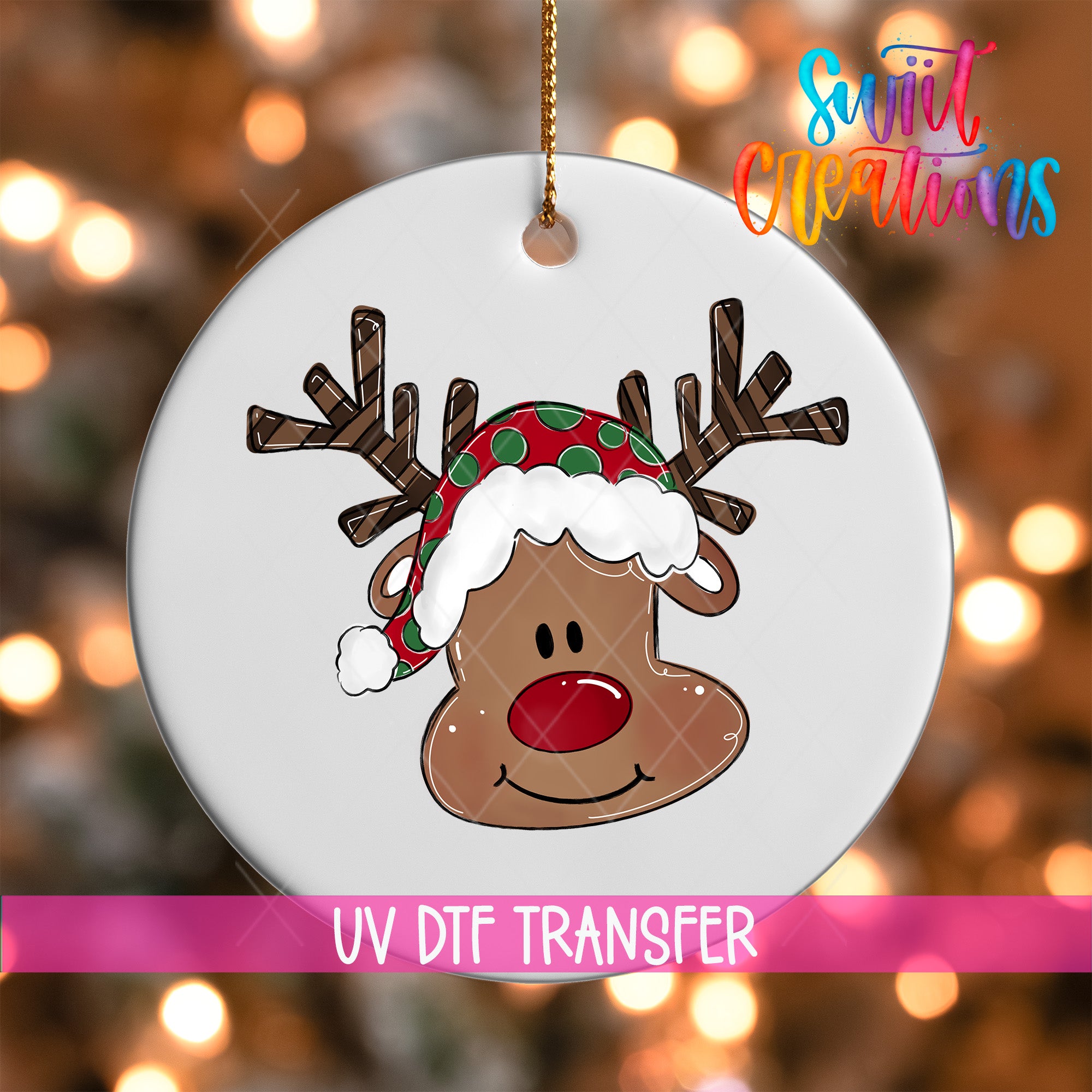 A white ornament with a cartoon reindeer wearing a red and green hat, with a pink ribbon around it.