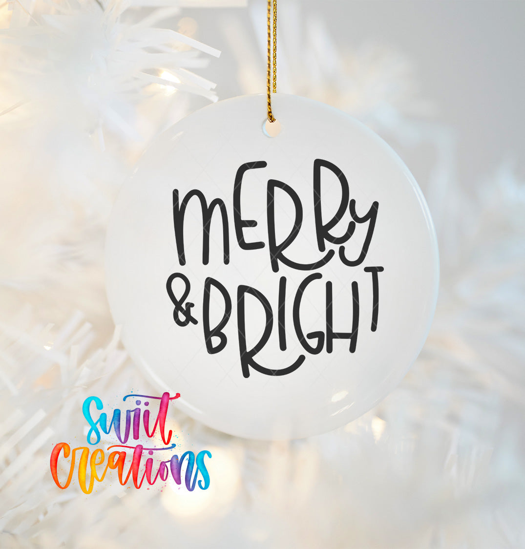 A white ornament with the text "MERRY & BRIGHT" written on it, hanging on a white background with a blurred background that appears to be a Christmas tree.