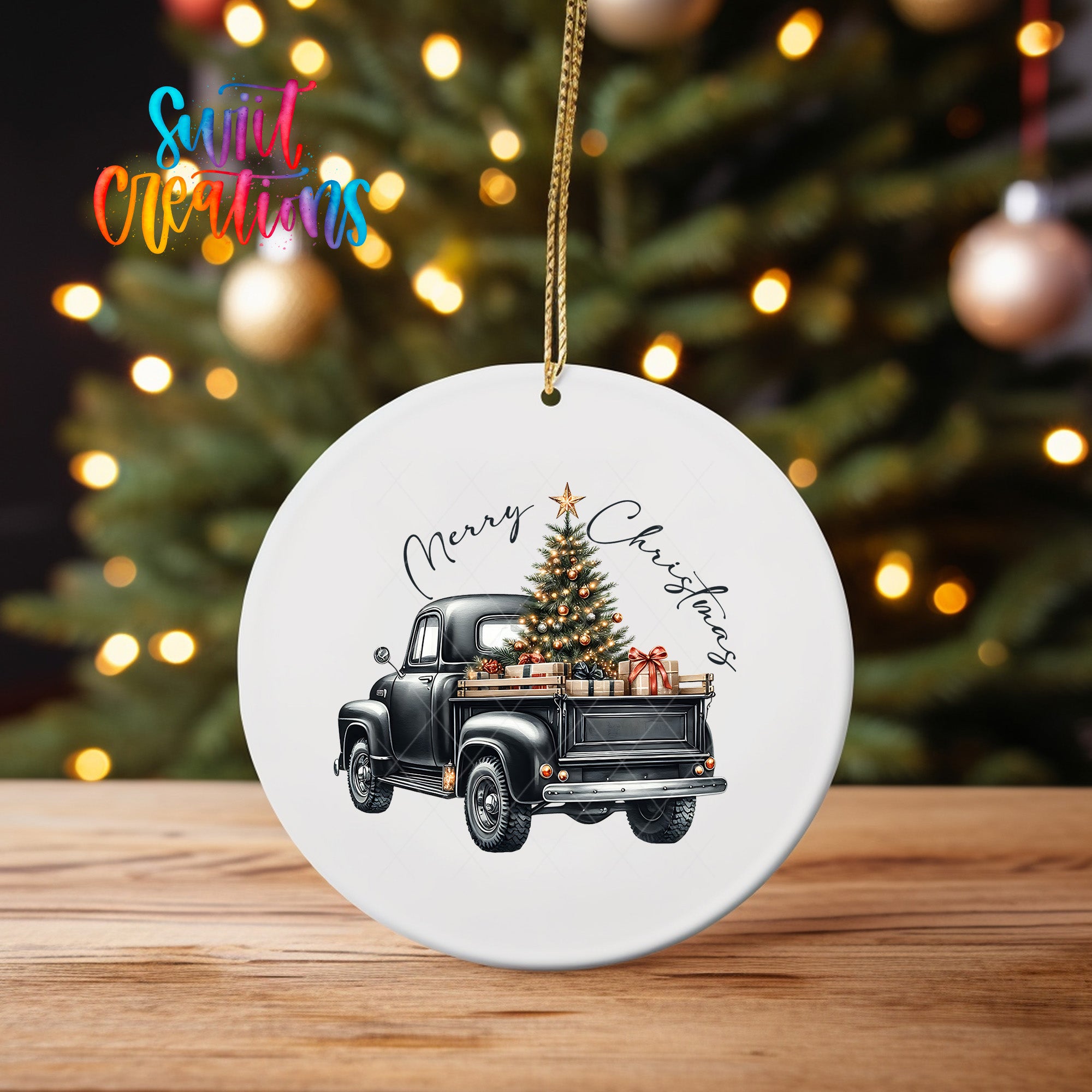 A white ceramic ornament featuring a black vintage truck with a Christmas tree in its bed, set against a blurred background of twinkling lights.
