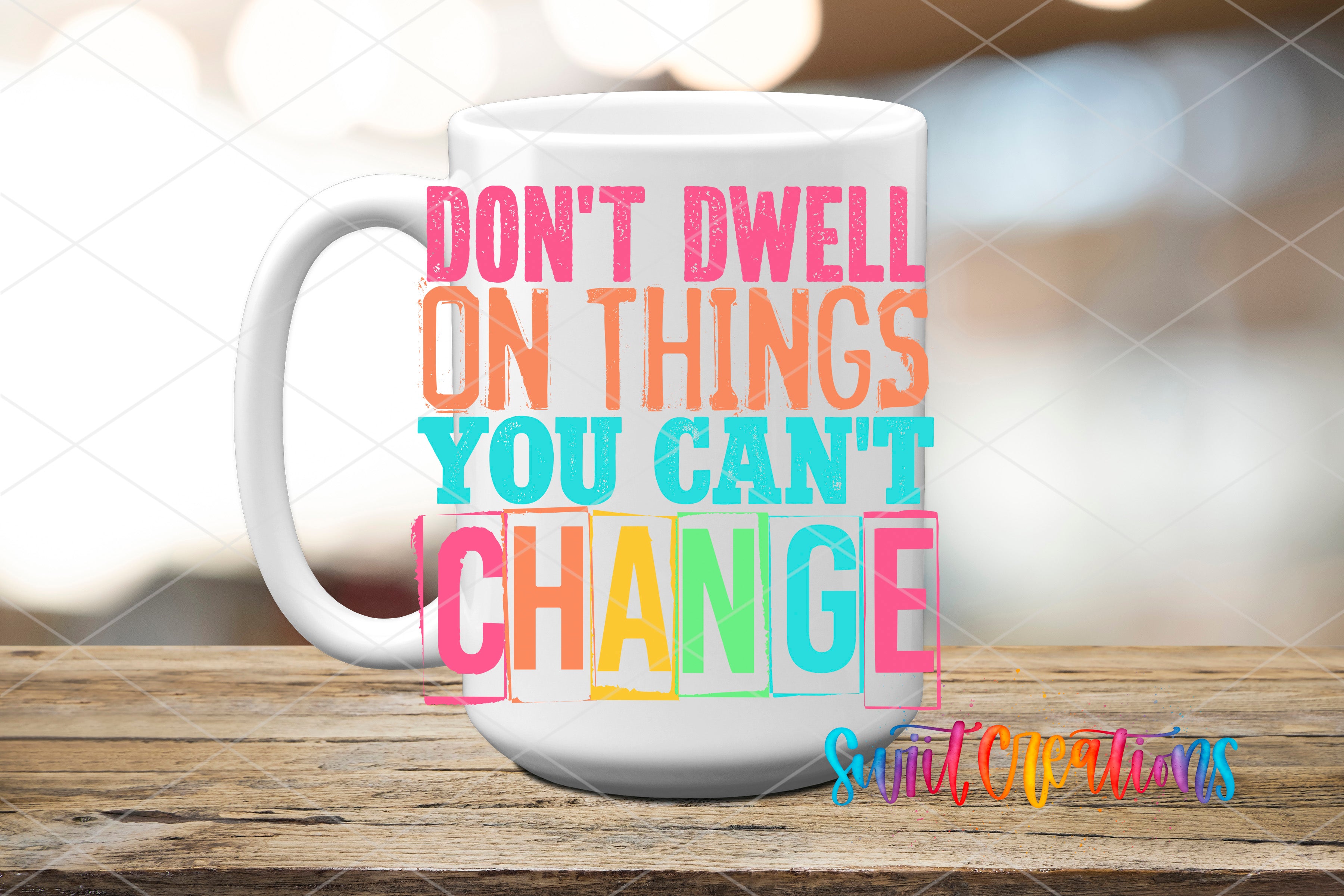 A white mug with colorful text on it, placed on a wooden surface.