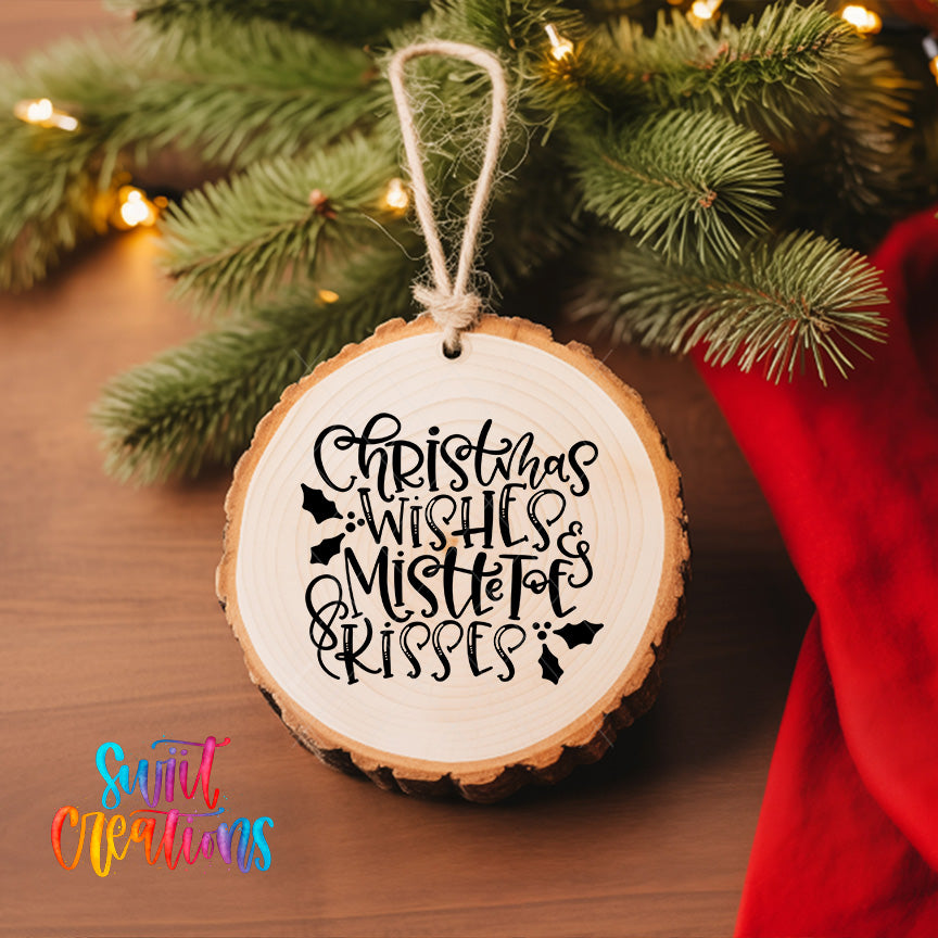 A wooden ornament with a text message that says "Christmas wishes, mistletoe, kisses" hanging on a Christmas tree.
