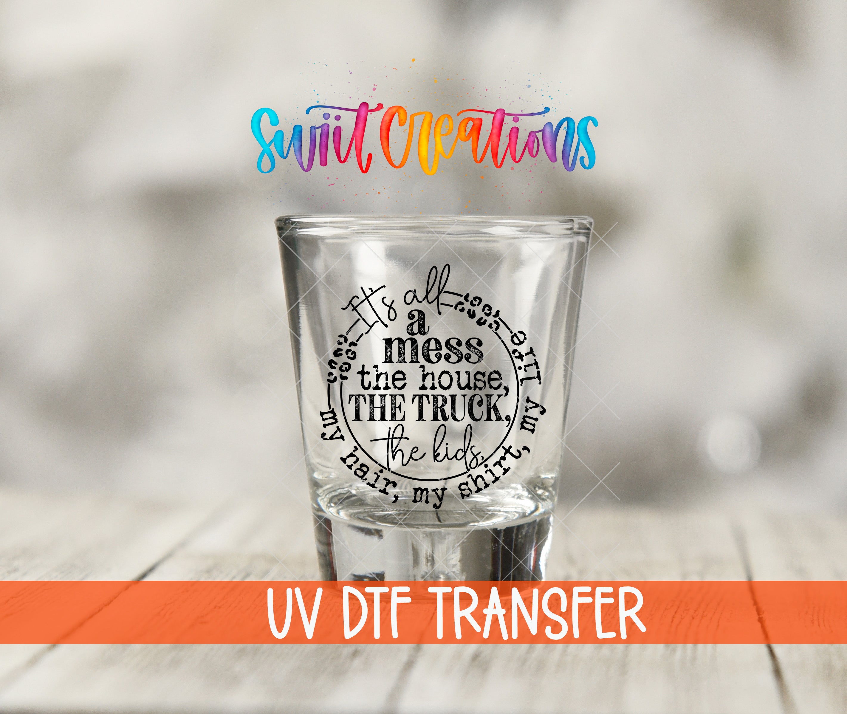 A shot glass with a printed text design on it, placed on a wooden surface.