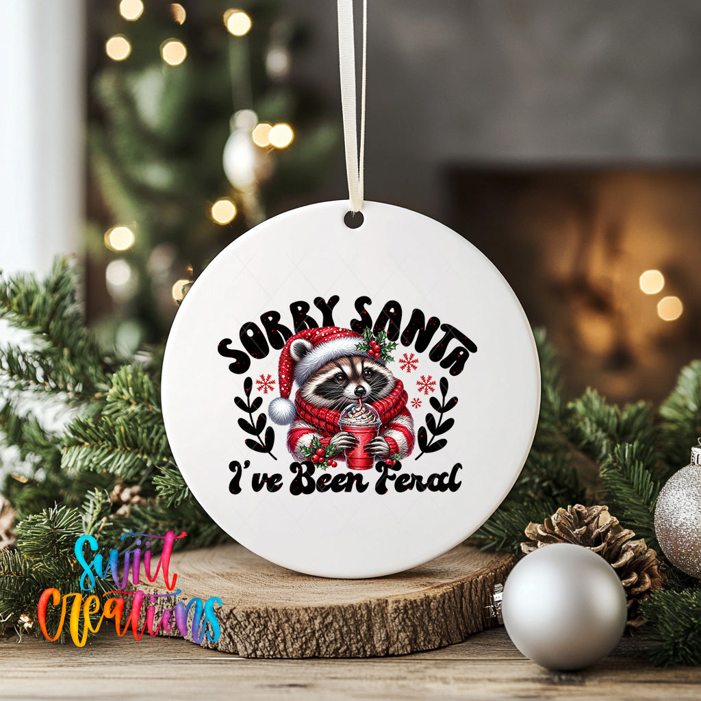 A white ceramic ornament with a raccoon wearing a Santa hat and scarf, holding a mug, surrounded by Christmas decorations and greenery.