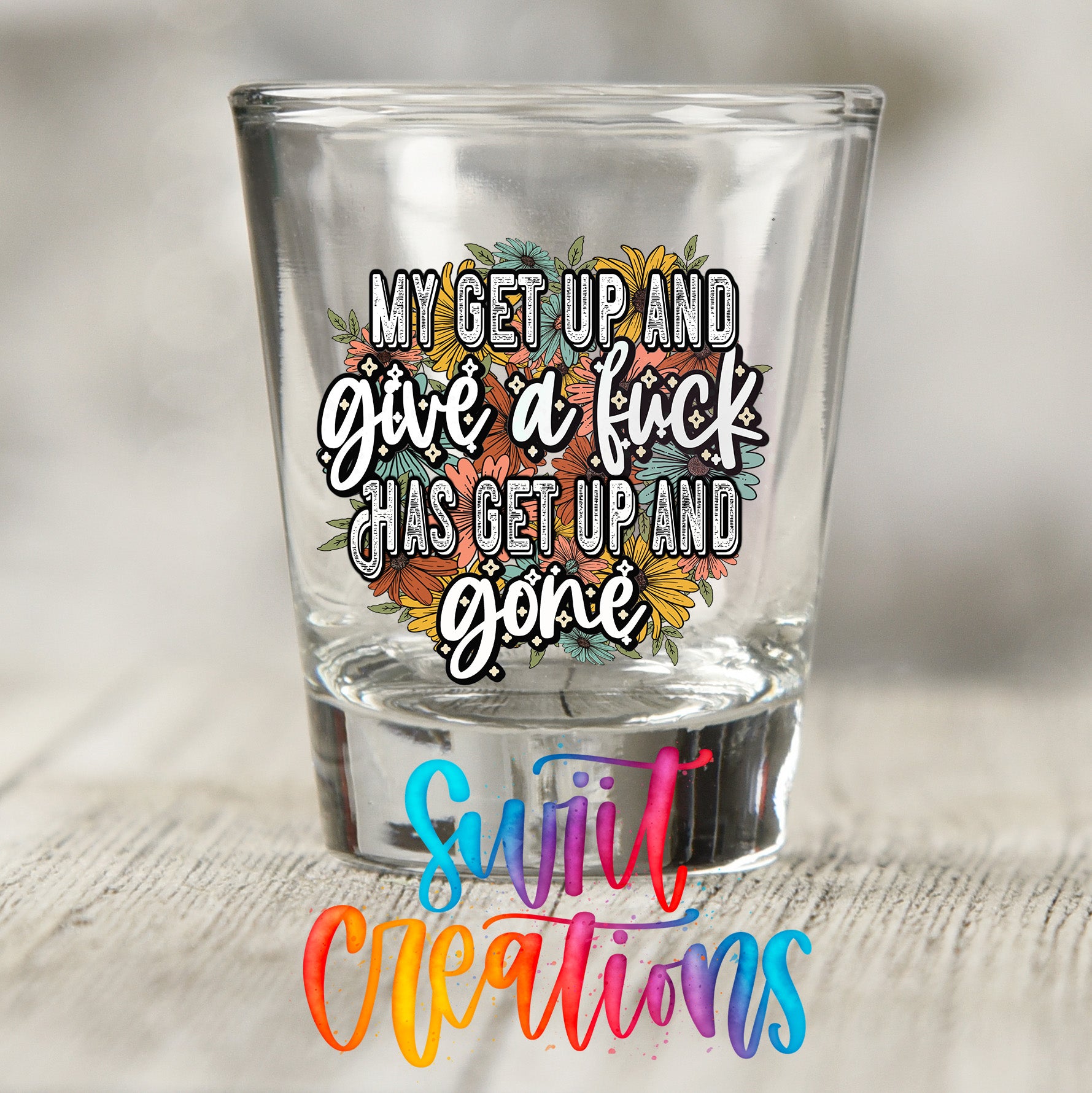 a shot glass with a colorful, hand-drawn quote on it, along with the text "Sweet Creations" in the bottom right corner.