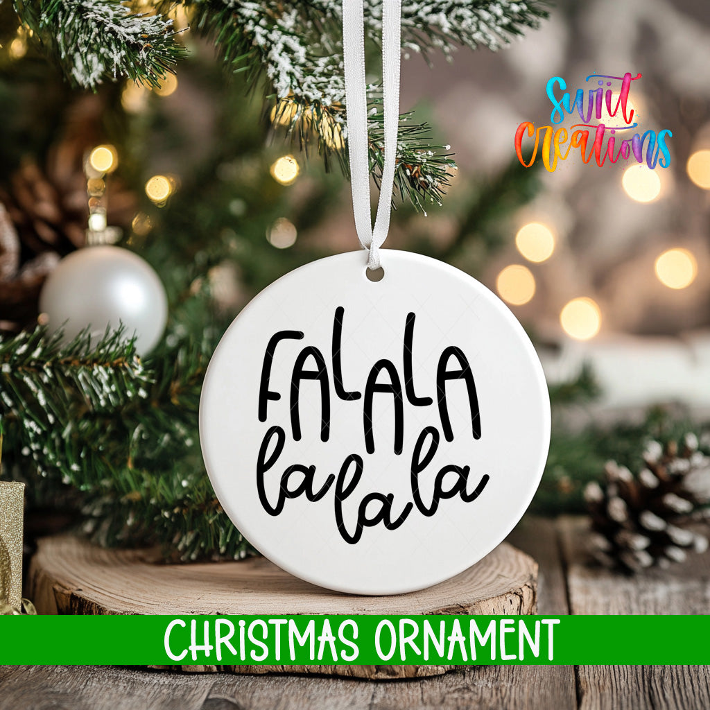 A white Christmas ornament with the text "FALA LA LA" hanging from a tree branch.
