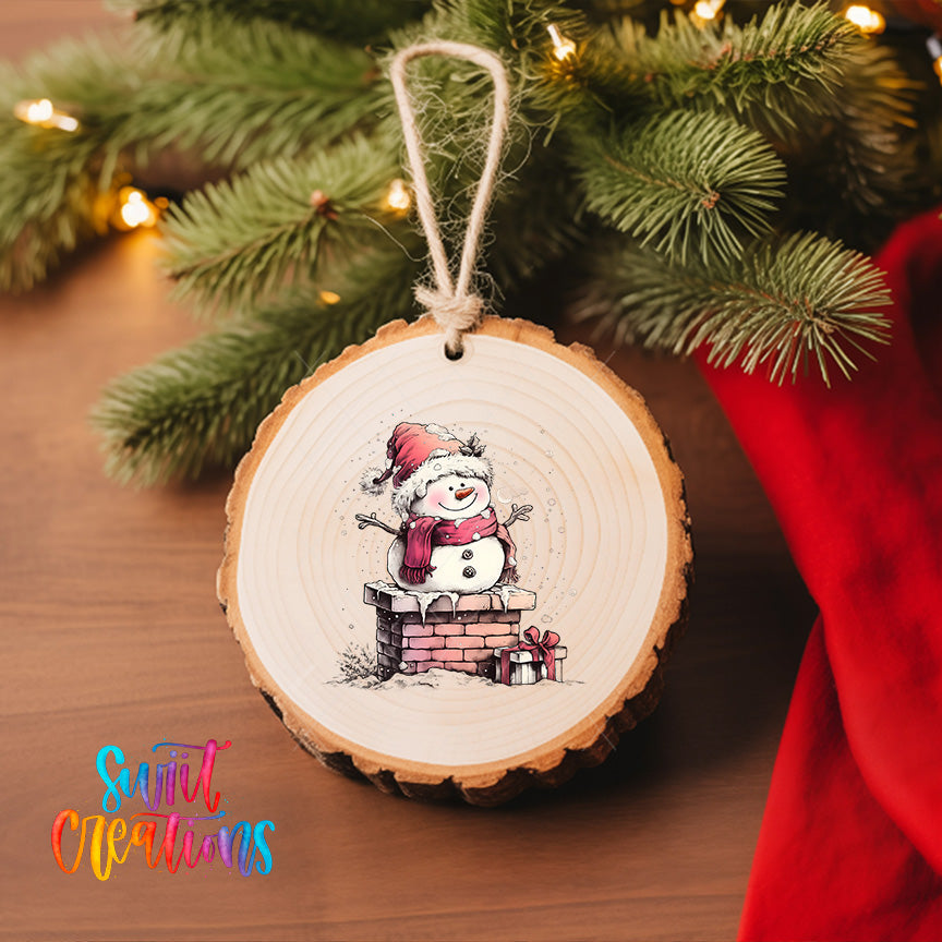 A wooden ornament with a snowman figure hanging from a string, surrounded by a Christmas tree and a red cloth.