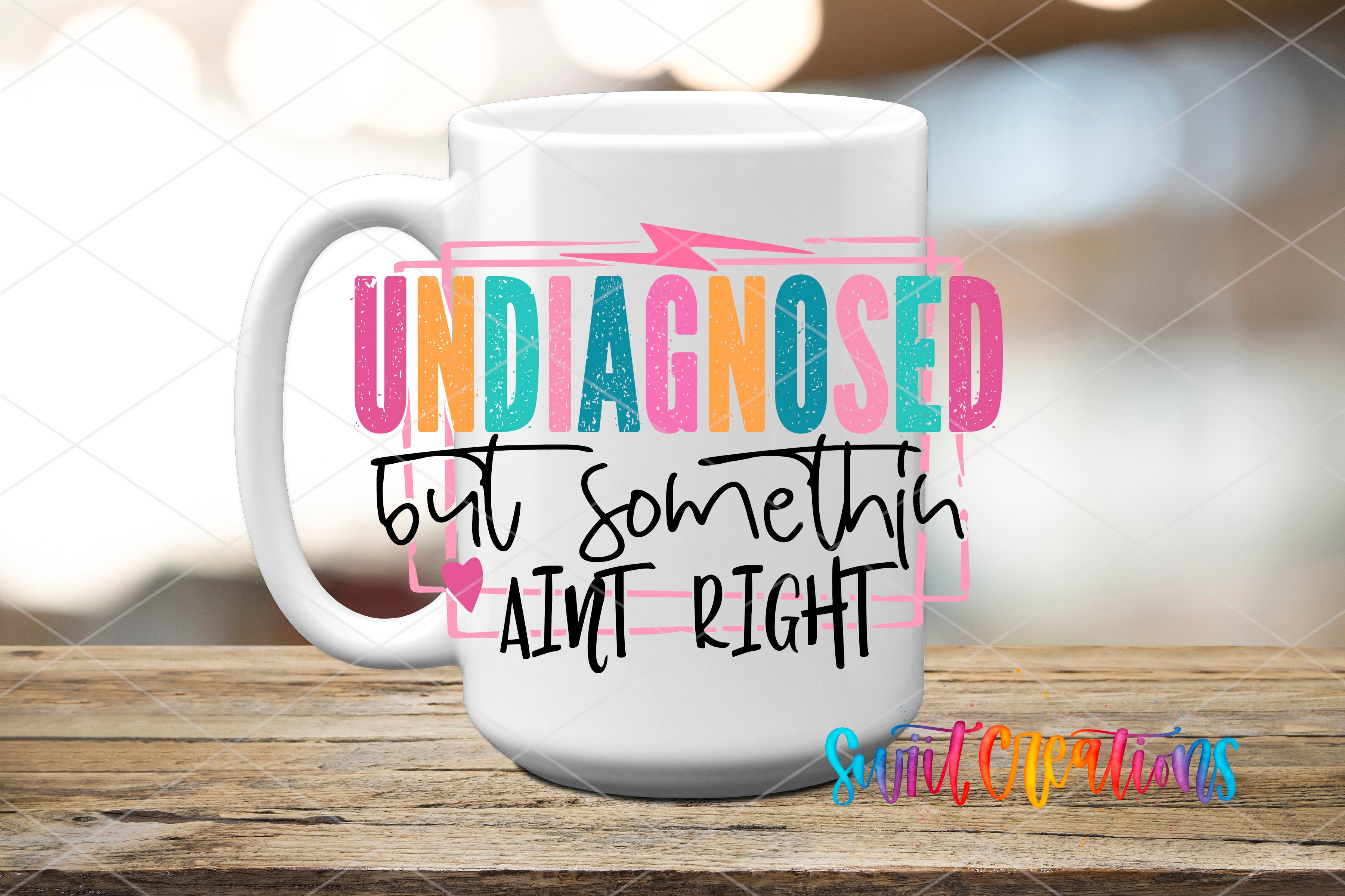 A white mug with colorful text and graphics on it, placed on a wooden surface.