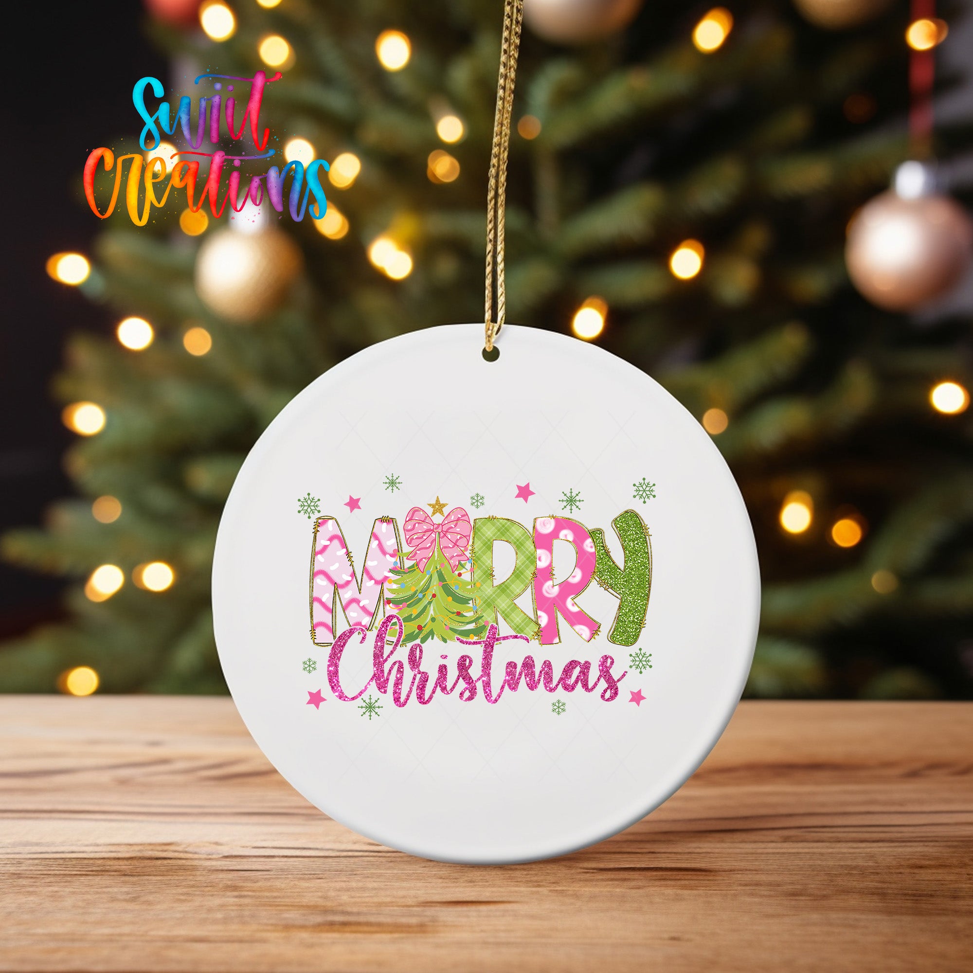 A white ceramic ornament with the text "Merry Christmas" in a colorful, festive font hangs on a wooden surface, with a blurred background of a Christmas tree and twinkling lights.