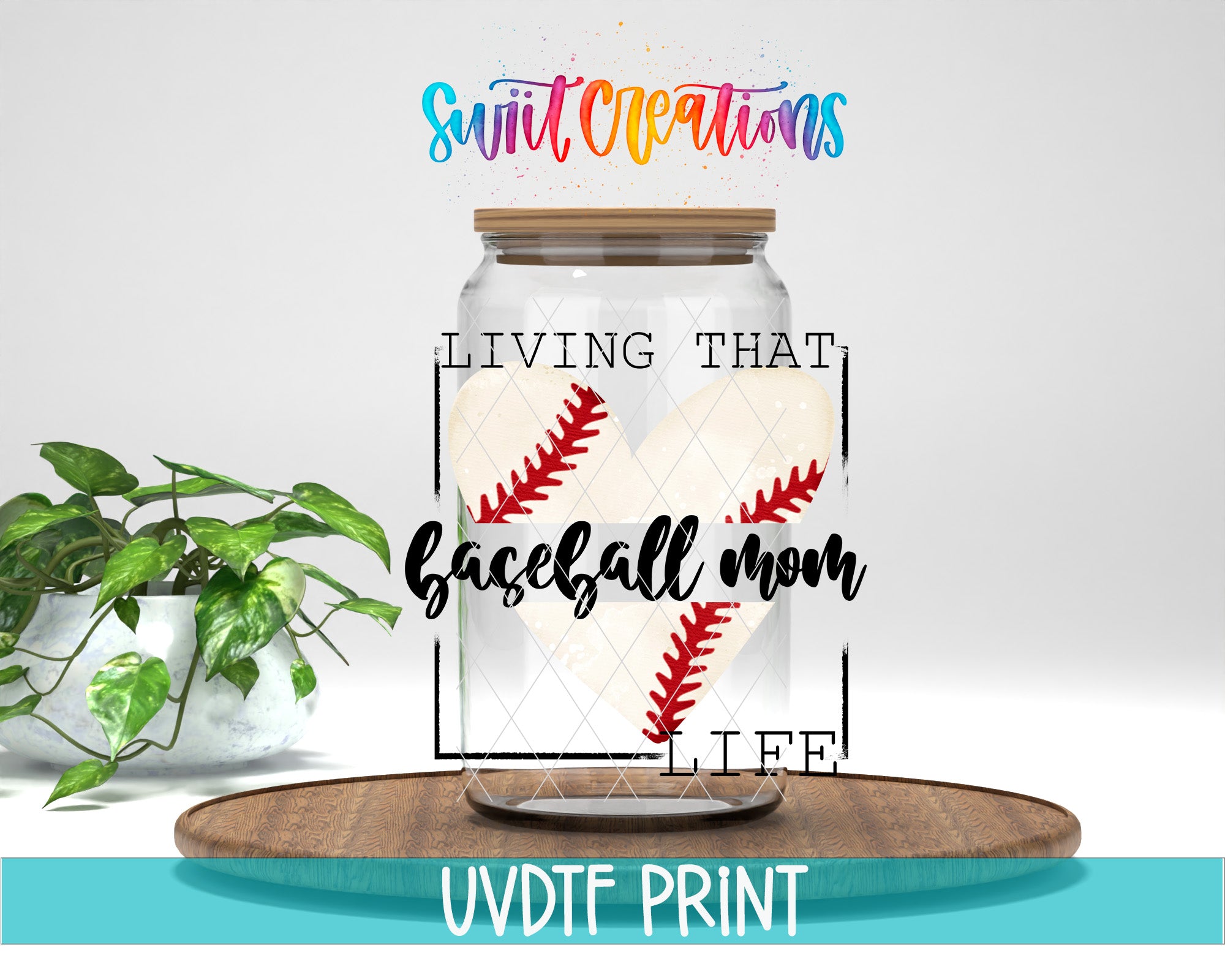 a glass jar with a baseball design inside, placed on a wooden surface. The jar has a lid and is surrounded by a plant. The text above the jar reads "Swift Creations" and "LIVING THAT BASEBALL MOM LIFE".