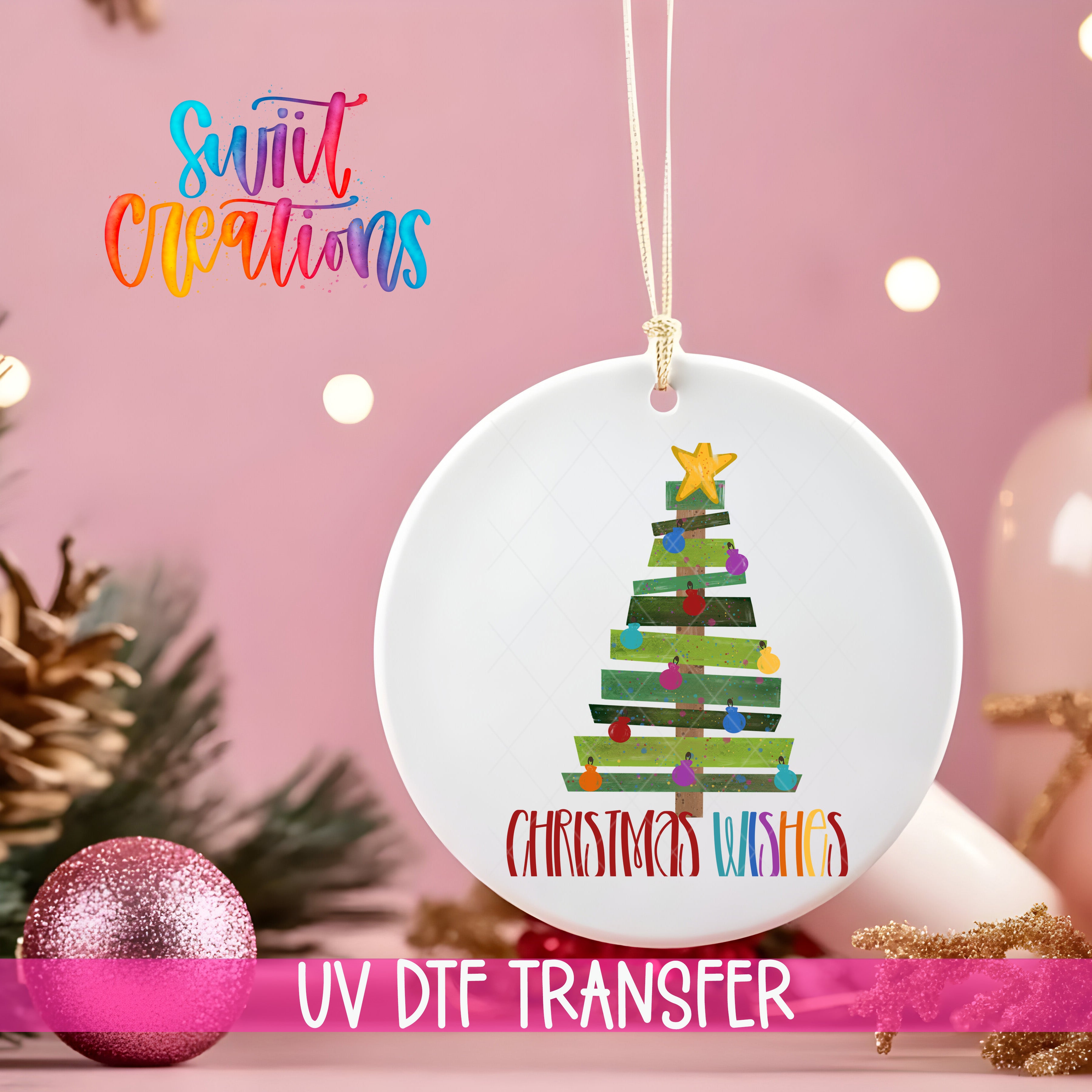 A white Christmas tree ornament with colorful ornaments and a star at the top, hanging on a string. The ornament has the text "Christmas Wishes" written on it. The ornament is set against a pink background with Christmas lights and pine cones.
