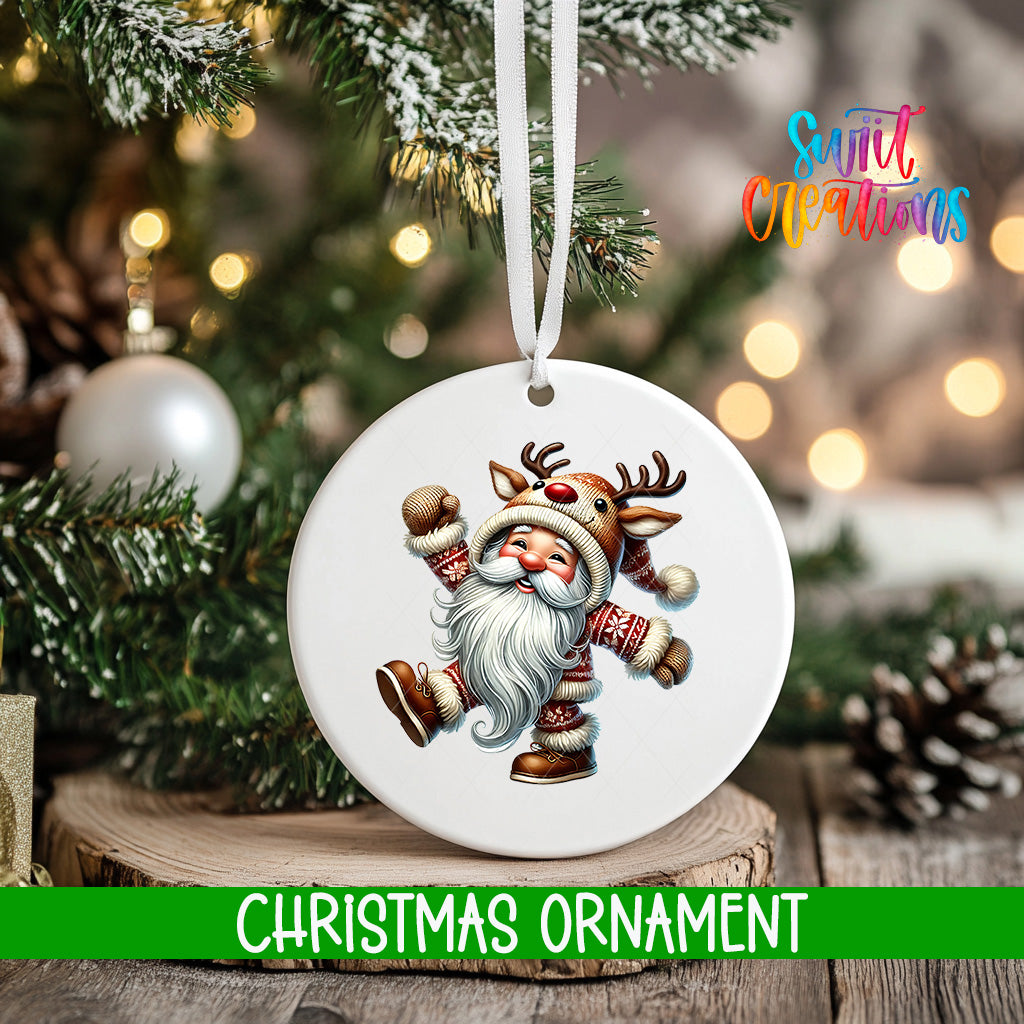 A white Christmas ornament featuring a smiling Santa Claus with antlers is hanging on a tree branch, surrounded by pine cones and other holiday decorations.