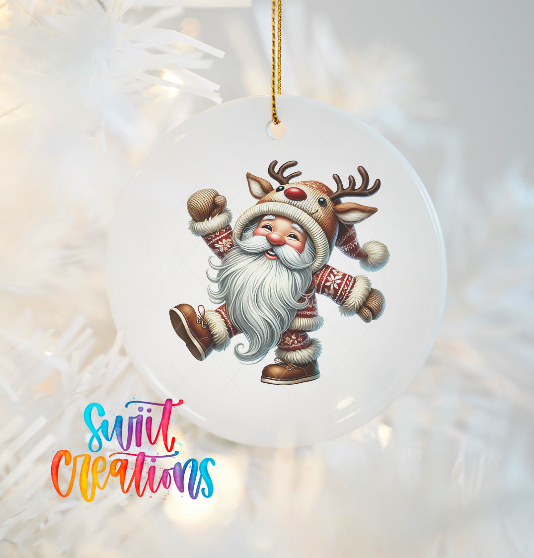 A white ornament featuring a smiling reindeer character with antlers, wearing a Santa Claus outfit, is hanging on a Christmas tree.