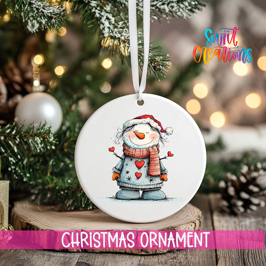 A white Christmas ornament featuring a snowman is hanging from a tree branch, with a blurred background of lights and greenery.