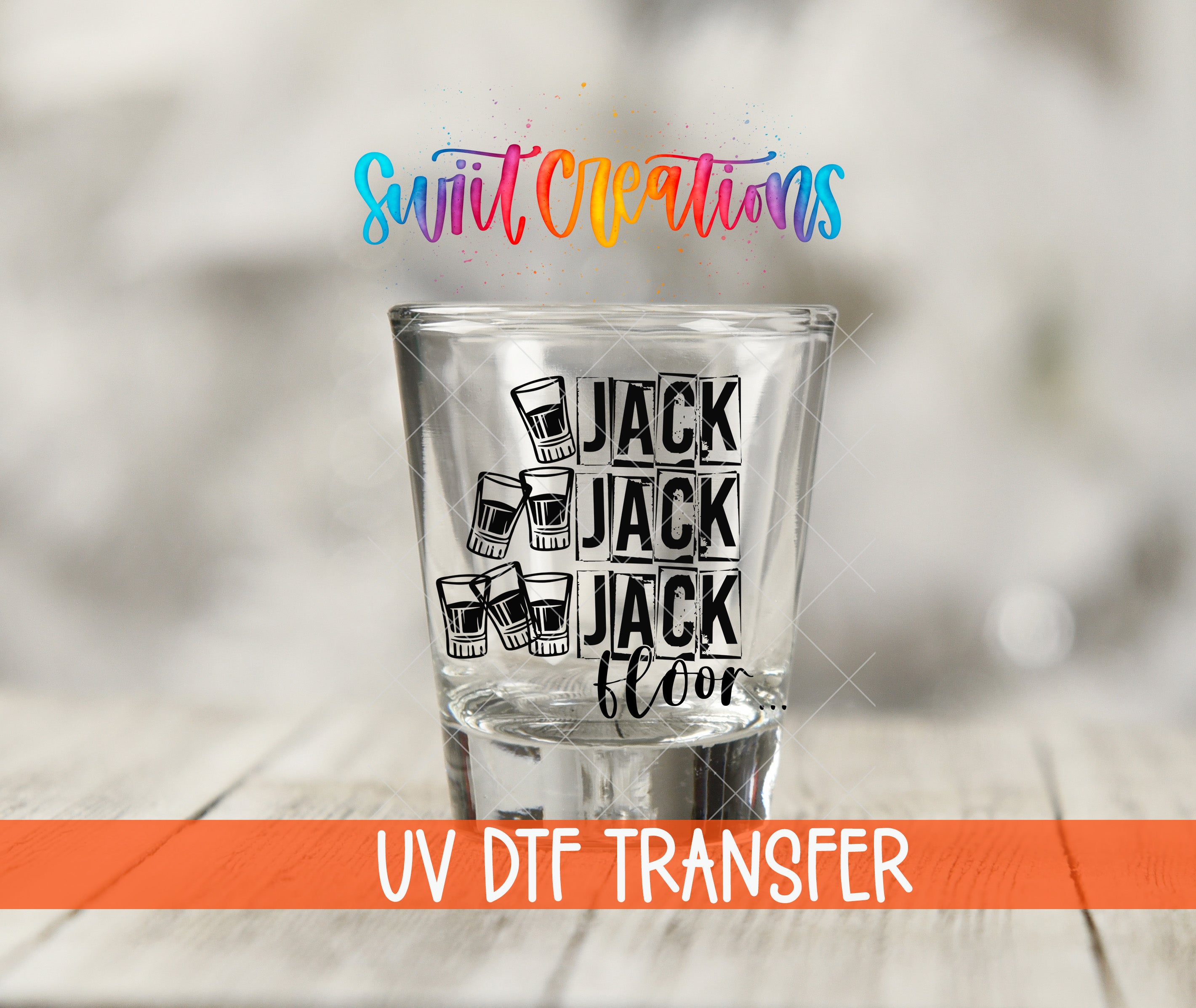 A shot glass with the text "JACK FLOOR" printed on it, along with illustrations of glasses, is placed on a wooden surface.