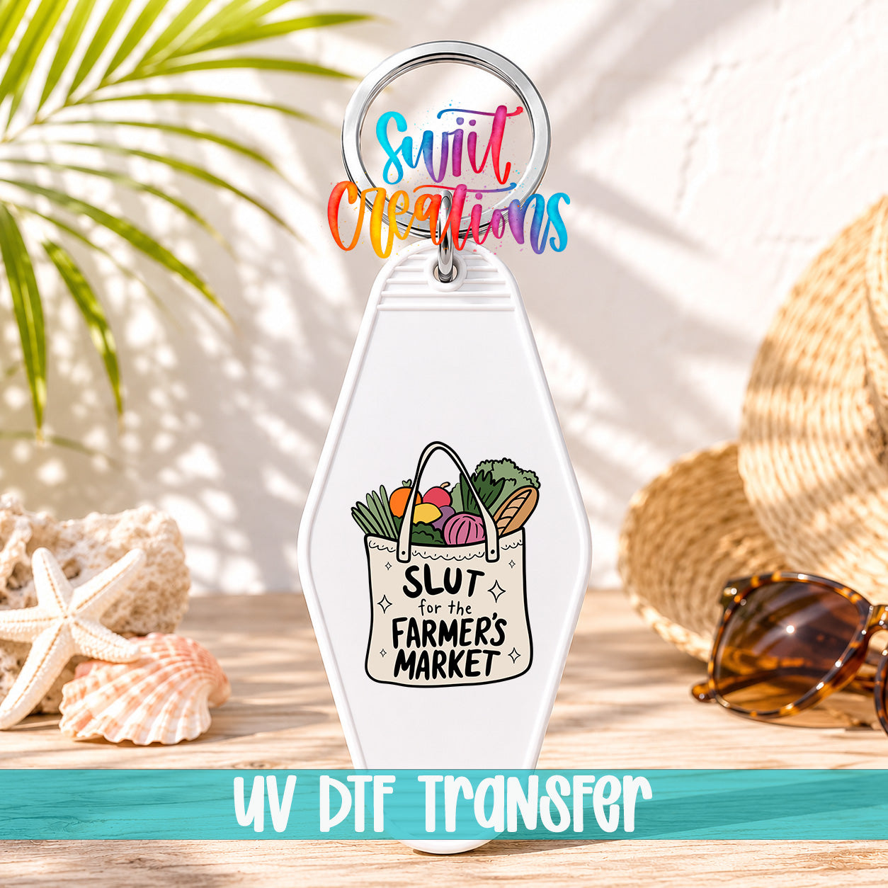 A keychain with a colorful design and text, placed on a wooden surface with sunglasses and a straw hat in the background.