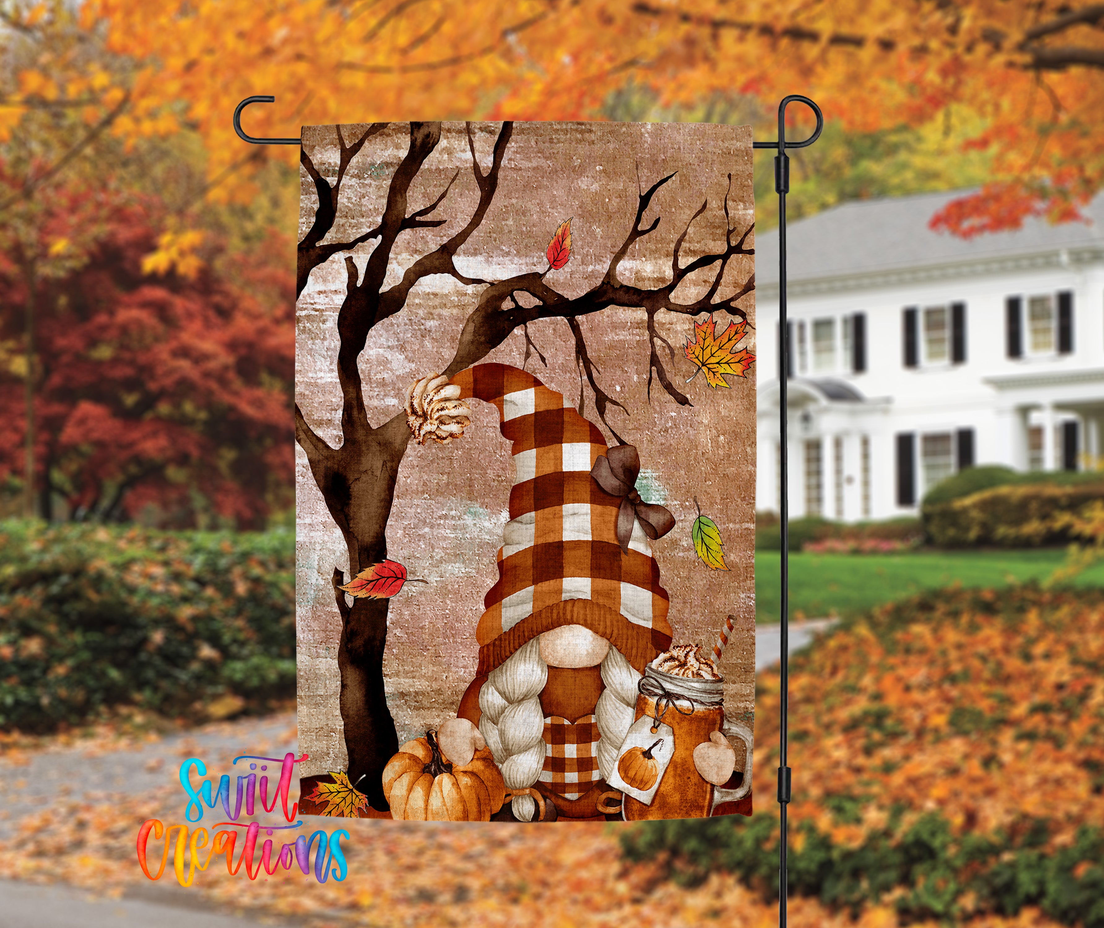 A colorful autumn-themed garden flag featuring a gnome, pumpkins, and leaves, with a white house in the background.