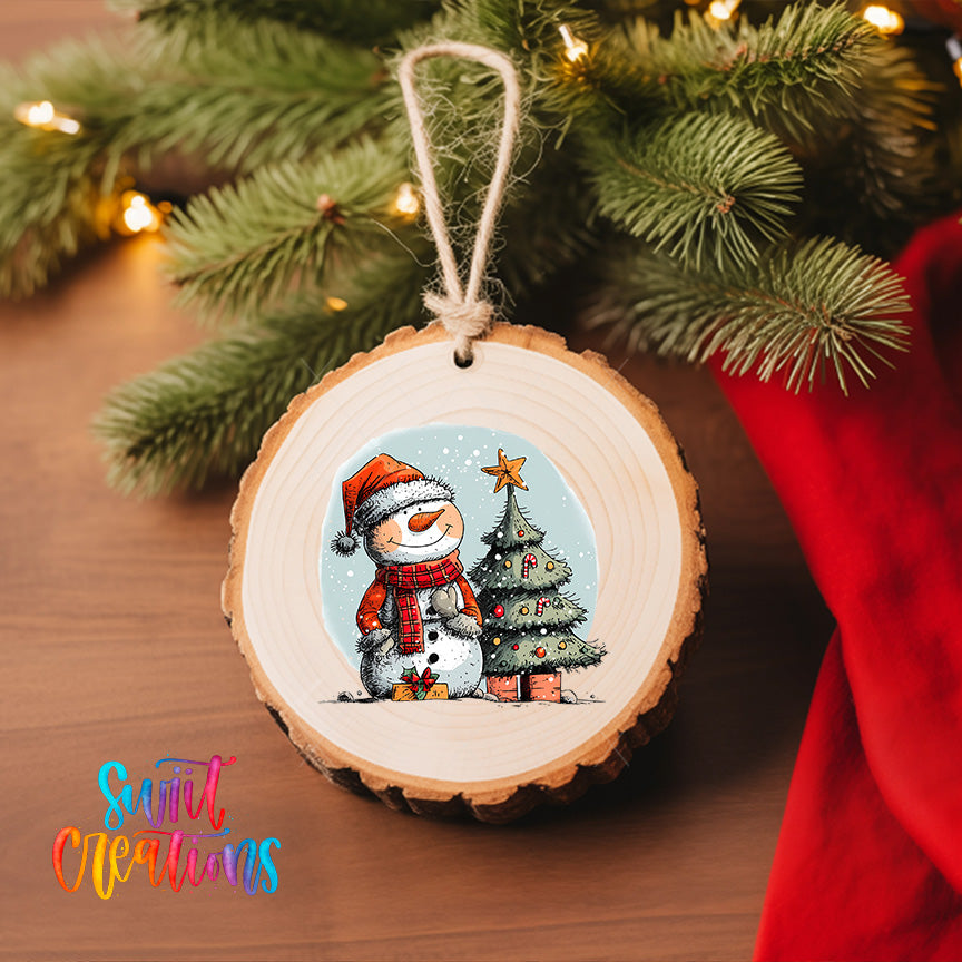 A wooden ornament featuring a snowman and a Christmas tree, hanging on a Christmas tree with a red cloth.
