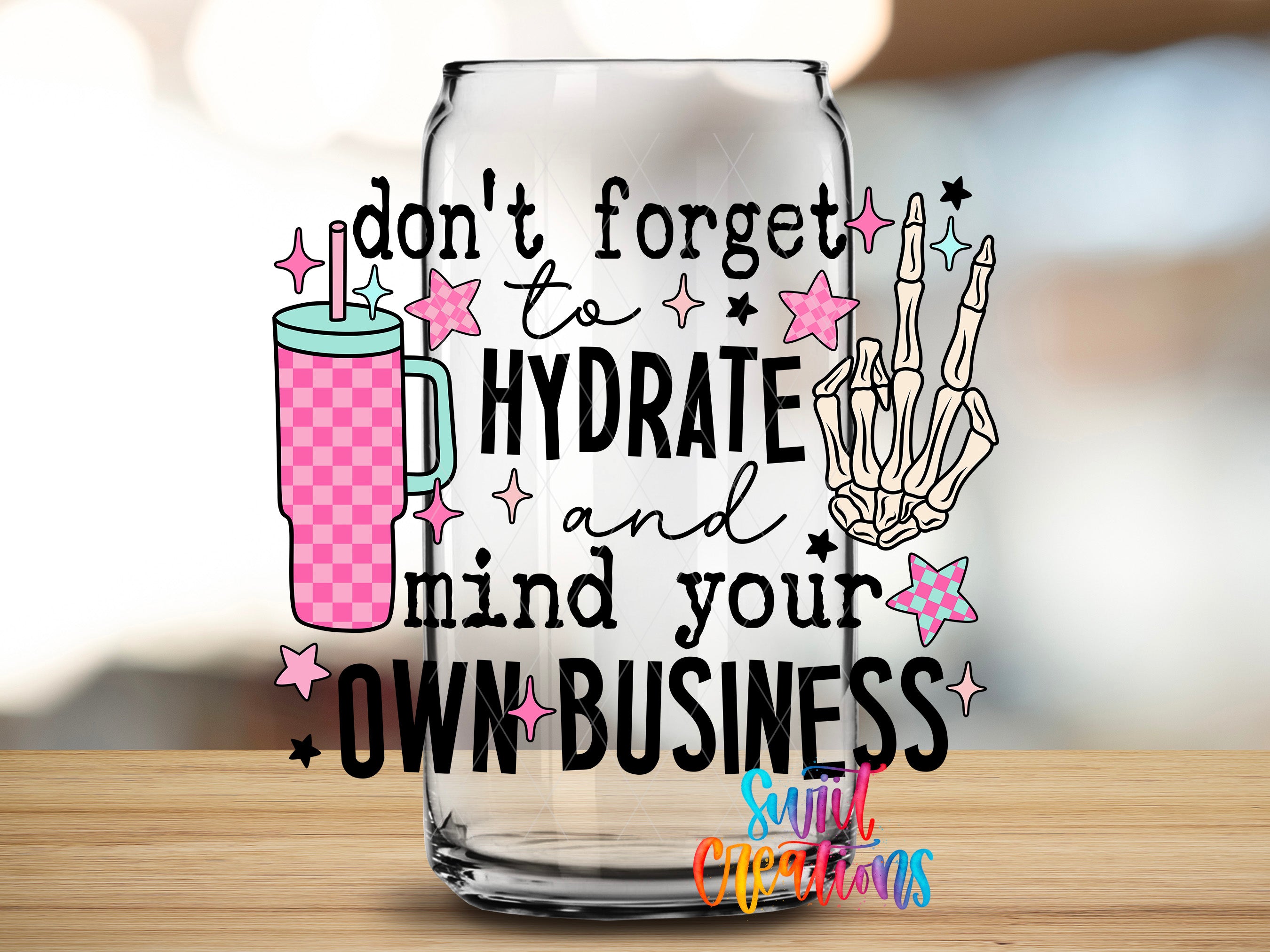 a clear glass with a text and graphic design on it, placed on a wooden surface.
