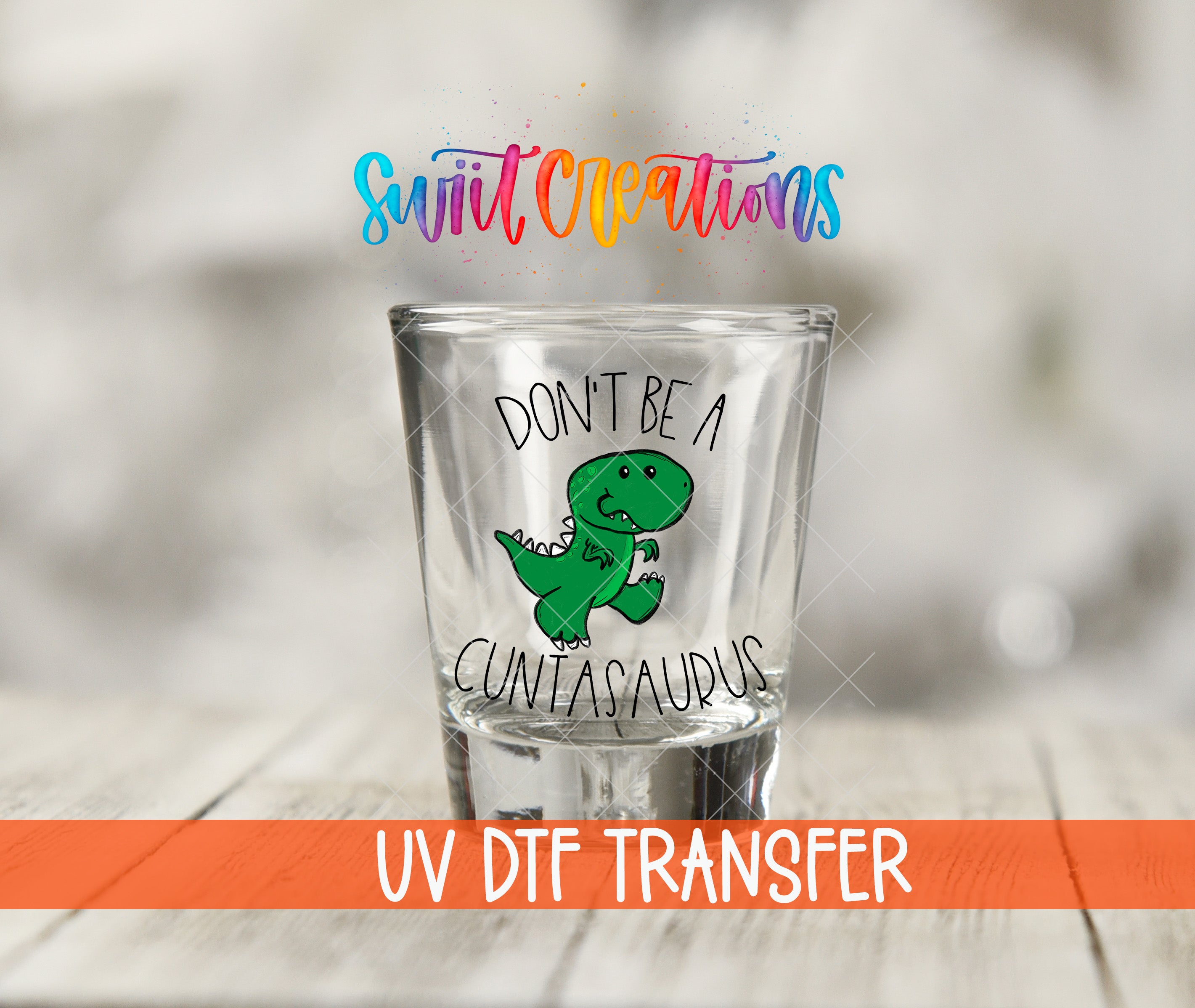 A shot glass with a cartoon dinosaur and the text "DON'T BE A CUNTAASAURUS" printed on it.
