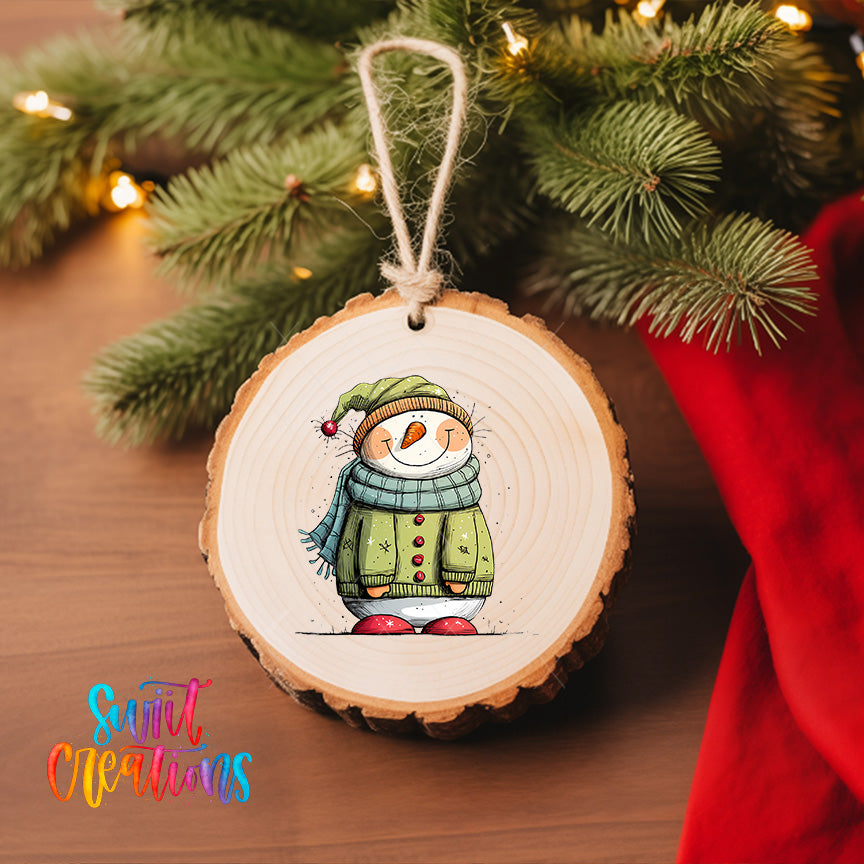 A wooden ornament featuring a cartoon snowman is hanging on a Christmas tree, surrounded by pine branches and twinkling lights.