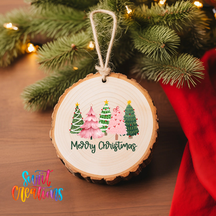 A wooden ornament with a festive design hangs on a Christmas tree, surrounded by twinkling lights and greenery.