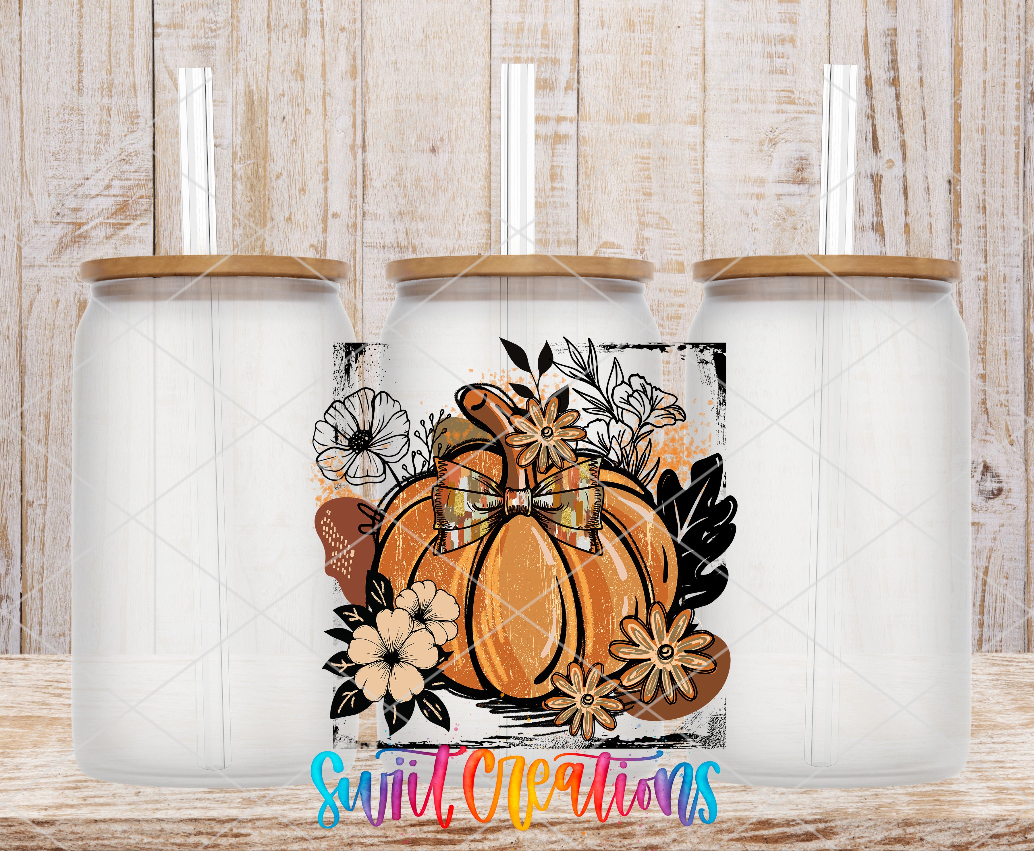 three glass jars with a pumpkin design and floral elements, set against a wooden background.