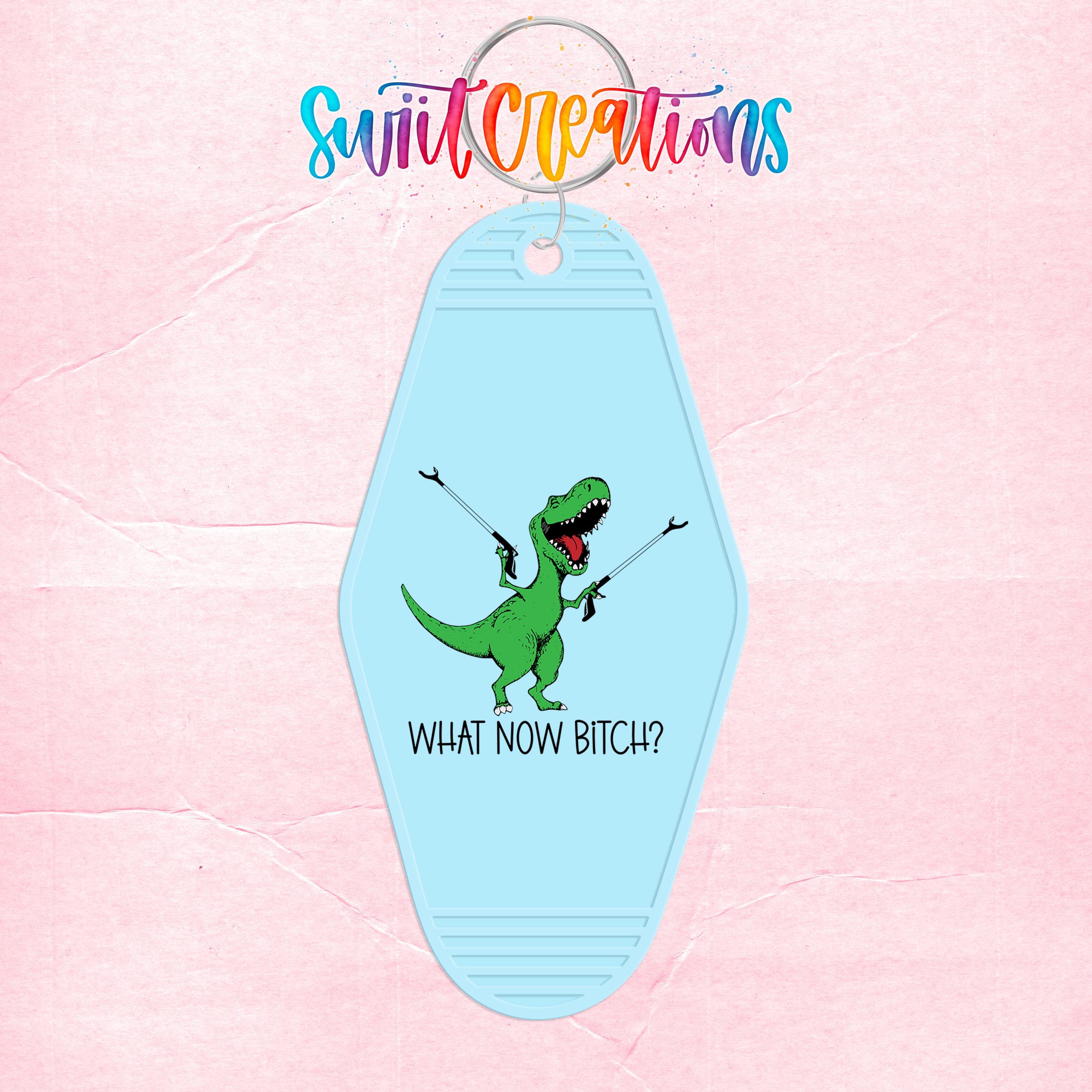 A keychain with a cartoon dinosaur holding a gun and the text "WHAT NOW BITCH?" printed on it.