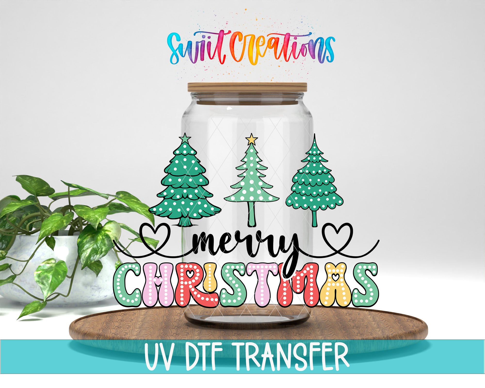 A glass jar with a lid, decorated with Christmas trees and a heart, along with the text "Merry Christmas" written on it. The jar is placed on a wooden surface, and there is a potted plant in the background.