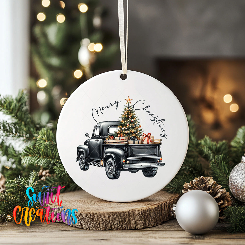 A white ceramic ornament featuring a black vintage truck with a Christmas tree in its bed, surrounded by holiday decorations such as ornaments and pine cones.