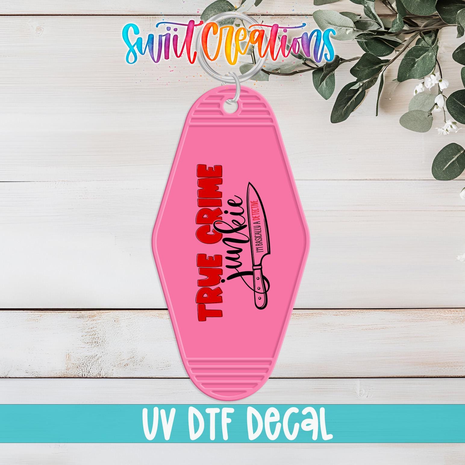 A pink keychain with the text "TRUE CRIME" and a graphic of a knife, placed on a white wooden surface.