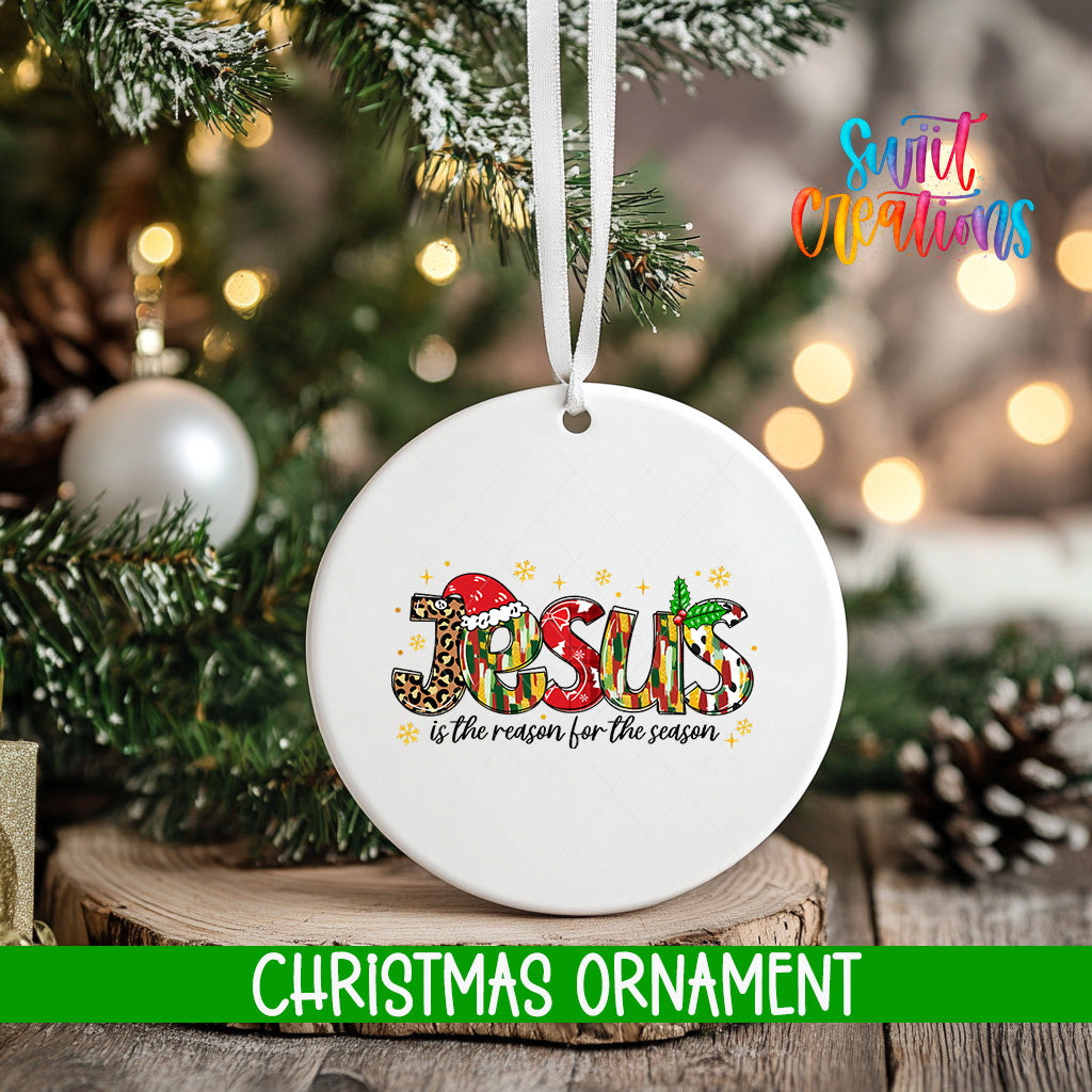 A white Christmas ornament with the word "JESUS" written on it, hanging from a tree branch.