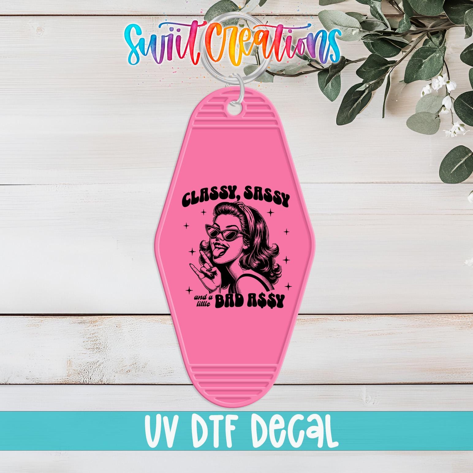 A pink keychain with a graphic design featuring a woman's face and the text "CLASSY SASSY and a little BAD ASSY" printed on it.