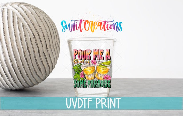 a colorful shot glass with a design that says "POUR ME A SHIT" and "SOME PARADISE" printed on it, along with illustrations of two drinks. The shot glass is placed next to a white ball, and there is text above the shot glass that reads "Swift Creations" and "UVDF PRINT".
