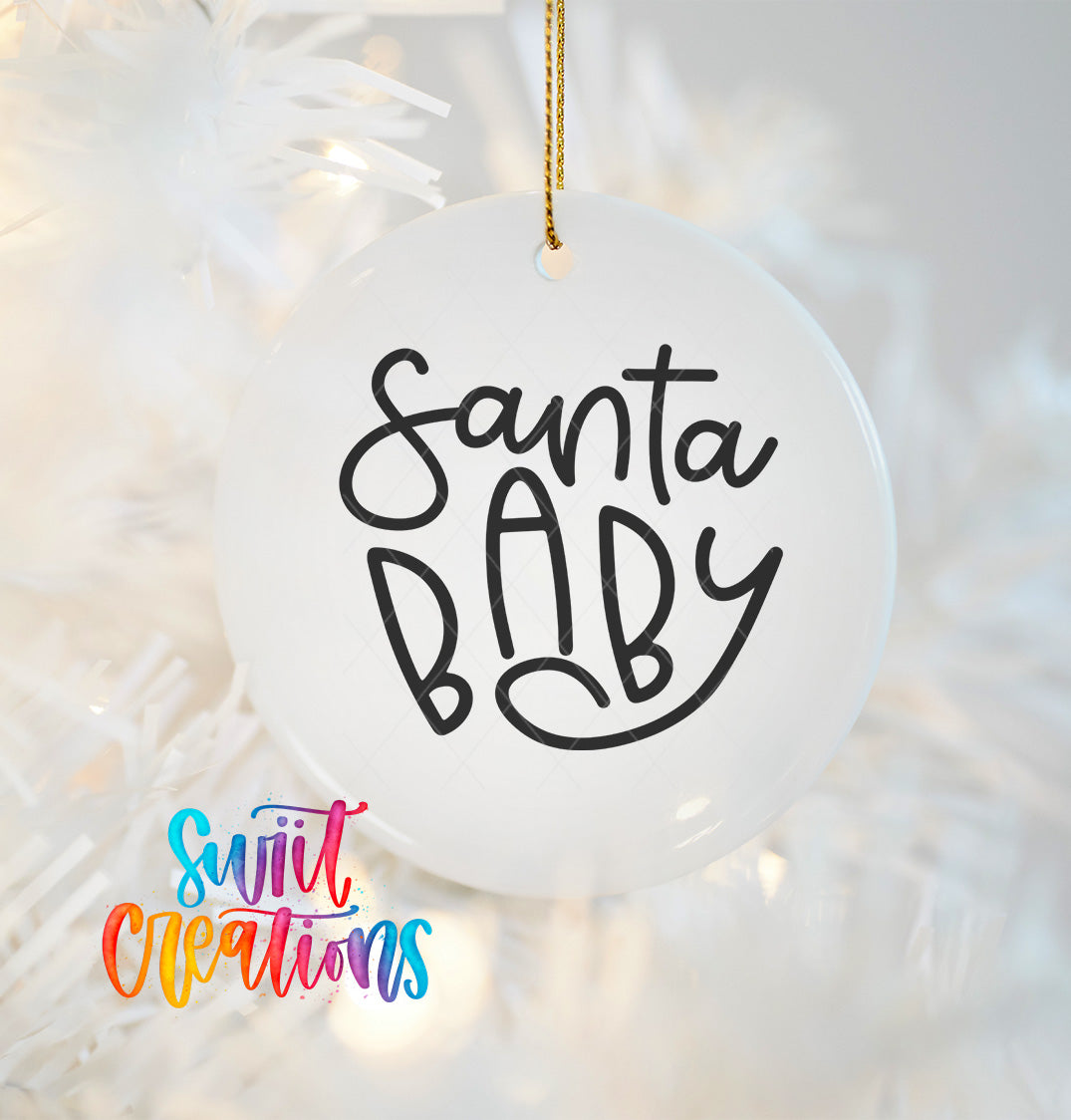 A white ornament with the text "Santa Baby" written on it, hanging on a Christmas tree.